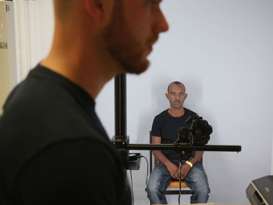 A refugee being photographed by German police as part of the registration process on 31 August