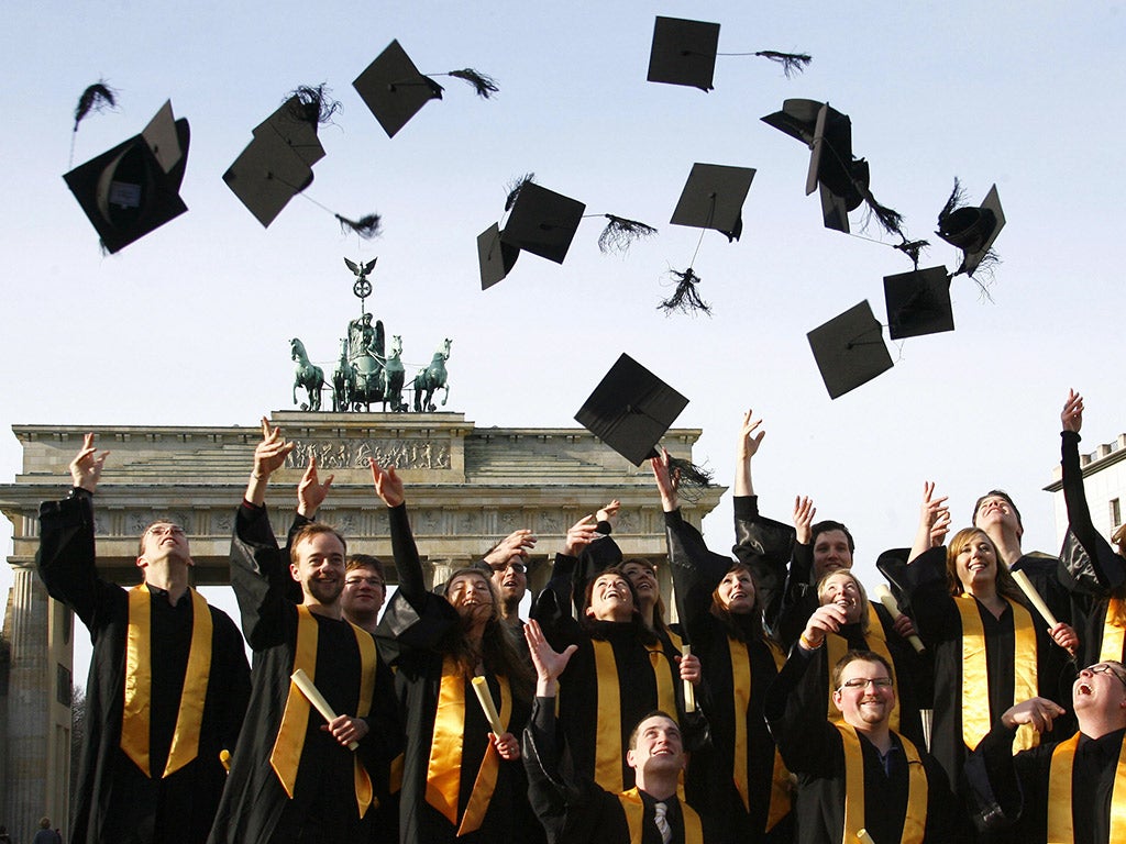 Graduates throw their doctoral caps in the air in front of the Brandenburg Gate in Berlin