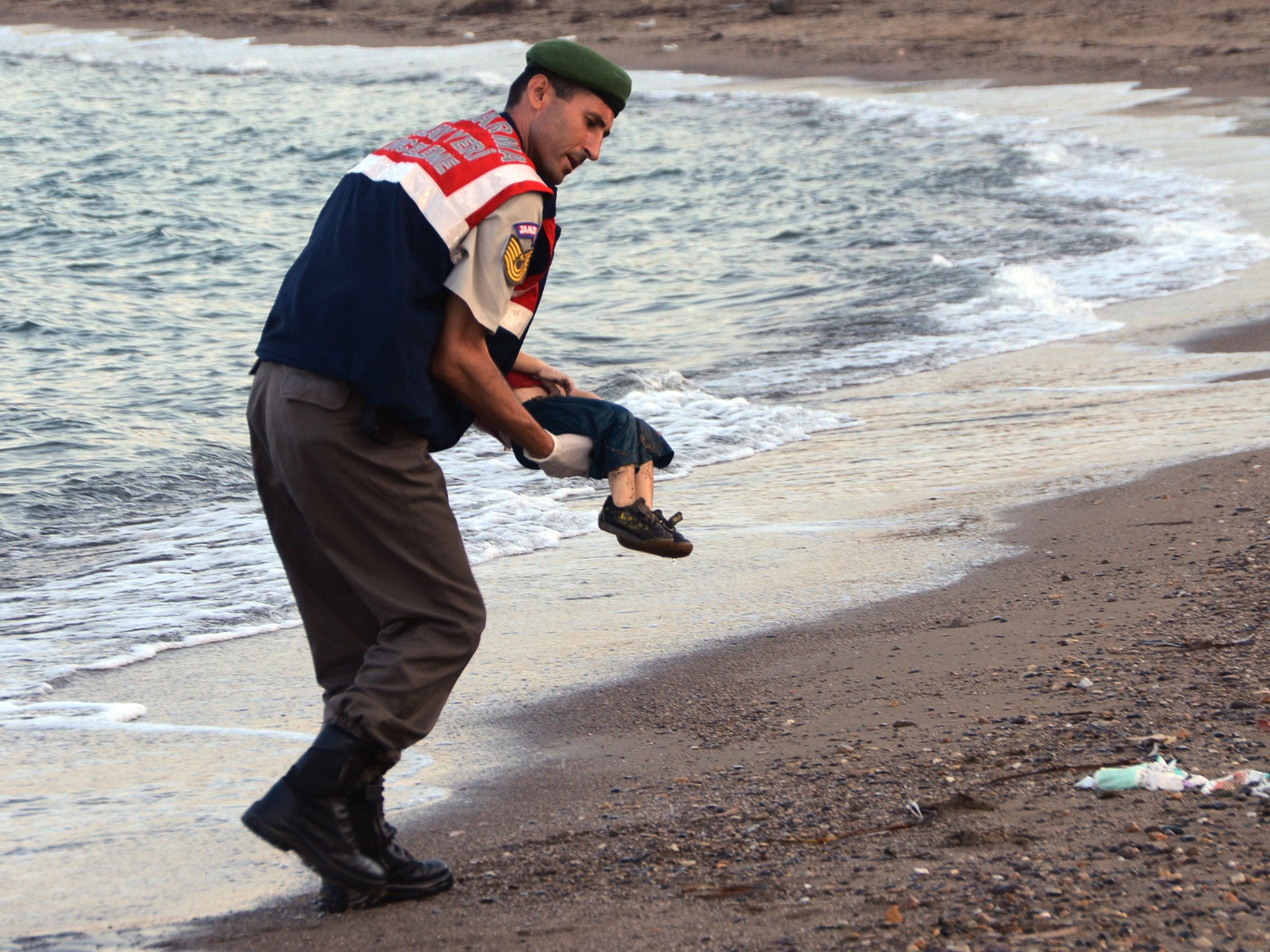 A paramilitary police officer carries the body of Aylan Kurdi, who drowned last September