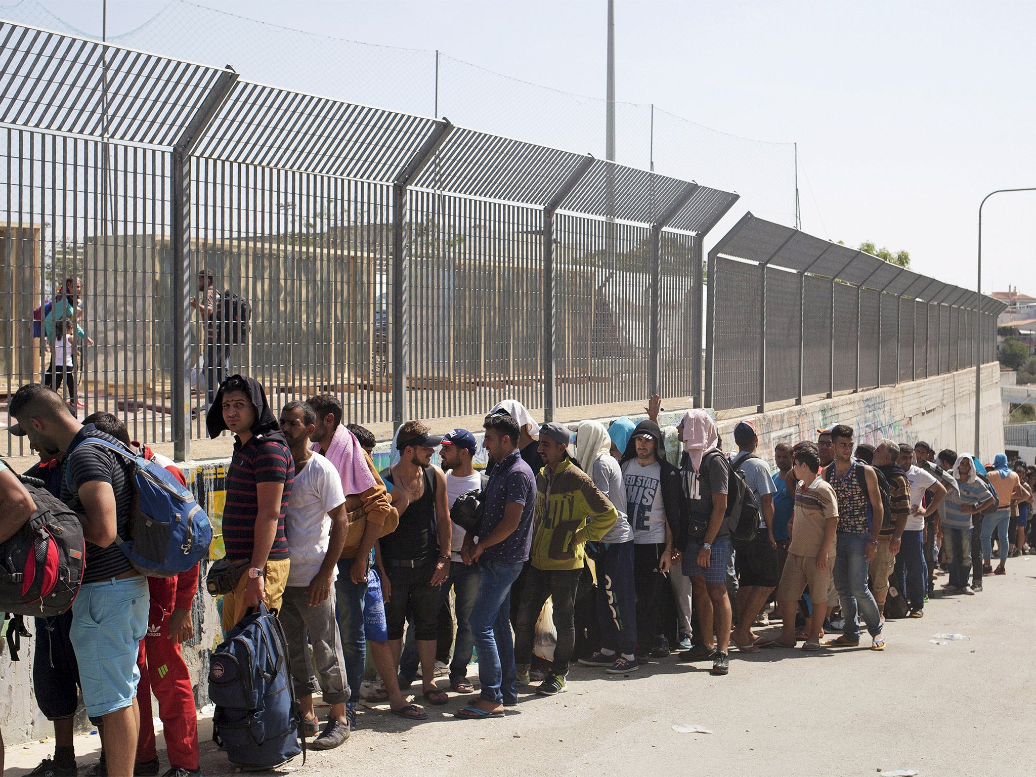 Refugees line up outside a soccer stadium used as a registration centre on the Greek island of Lesbos