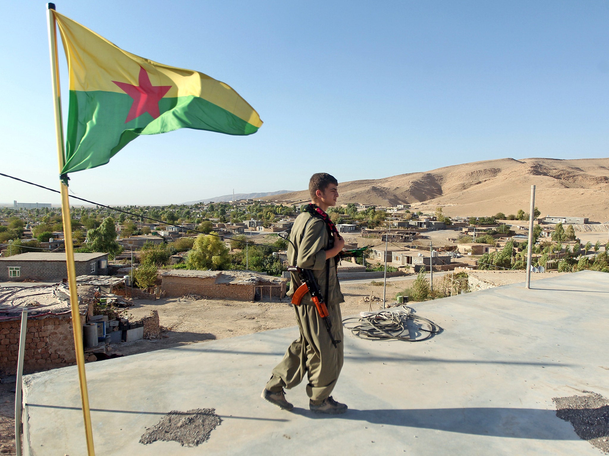 A Kurdistan Workers Party (PKK) fighter guards a post flying the group's flag in the town of Makhmur, northern Iraq