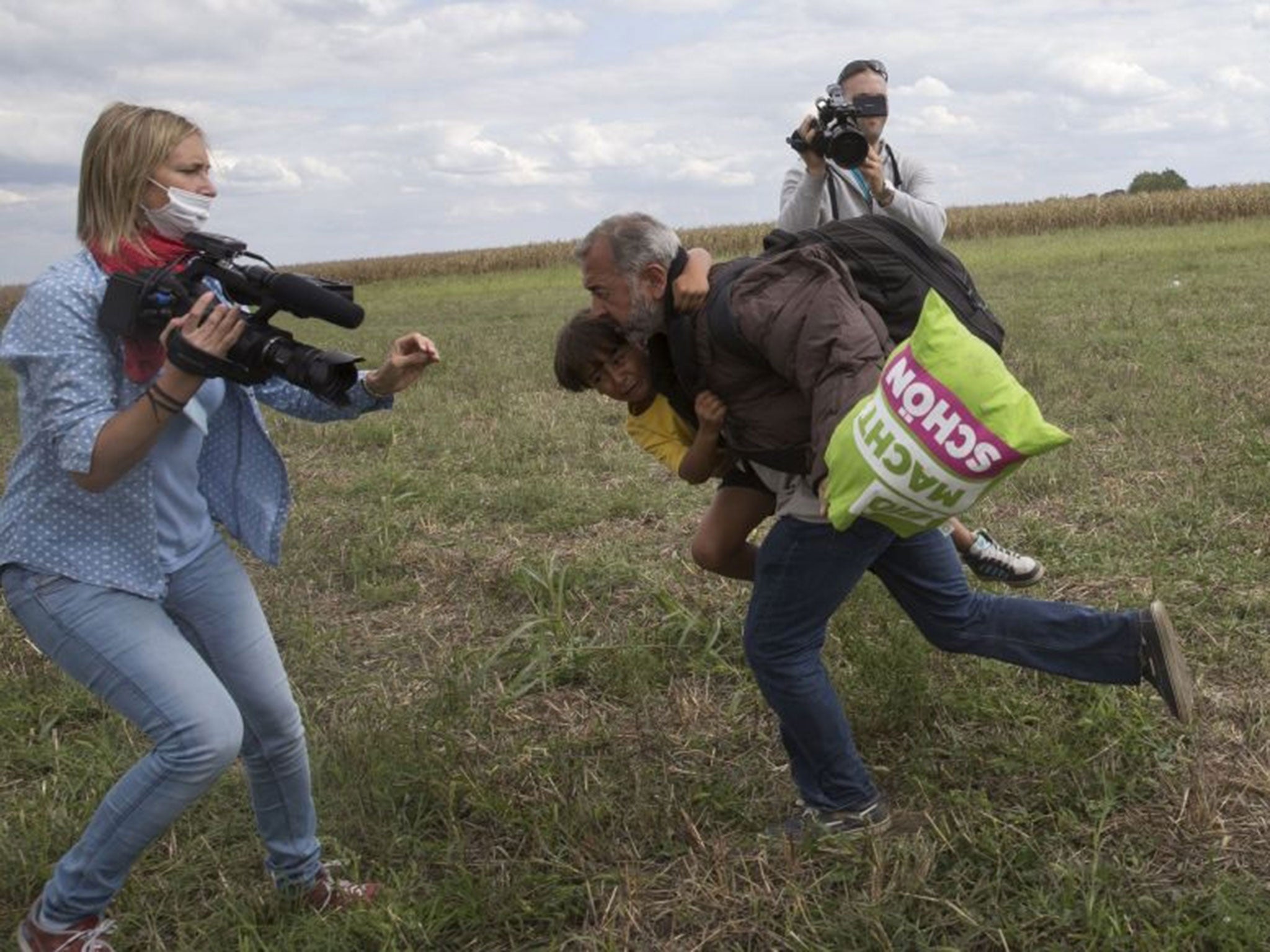 A refugee carrying a child falls runs past Ms László (Image: REUTERS/Marko Djurica)