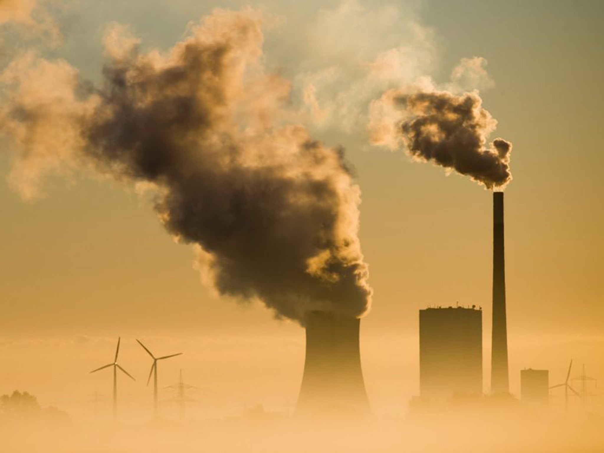 Sun glints off columns of smoke rising from the chimneys of a coal power plant in Hohehameln, Germany