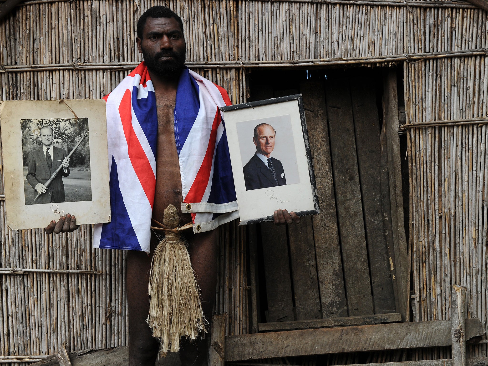 Sikor Natuan, the son of the local chief, holds two official portraits of Prince Phillip