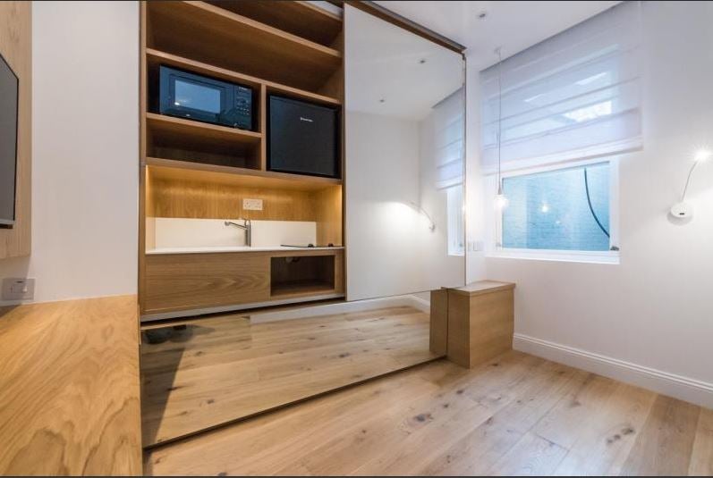 Kitchen unit is enclosed behind a sliding mirror door