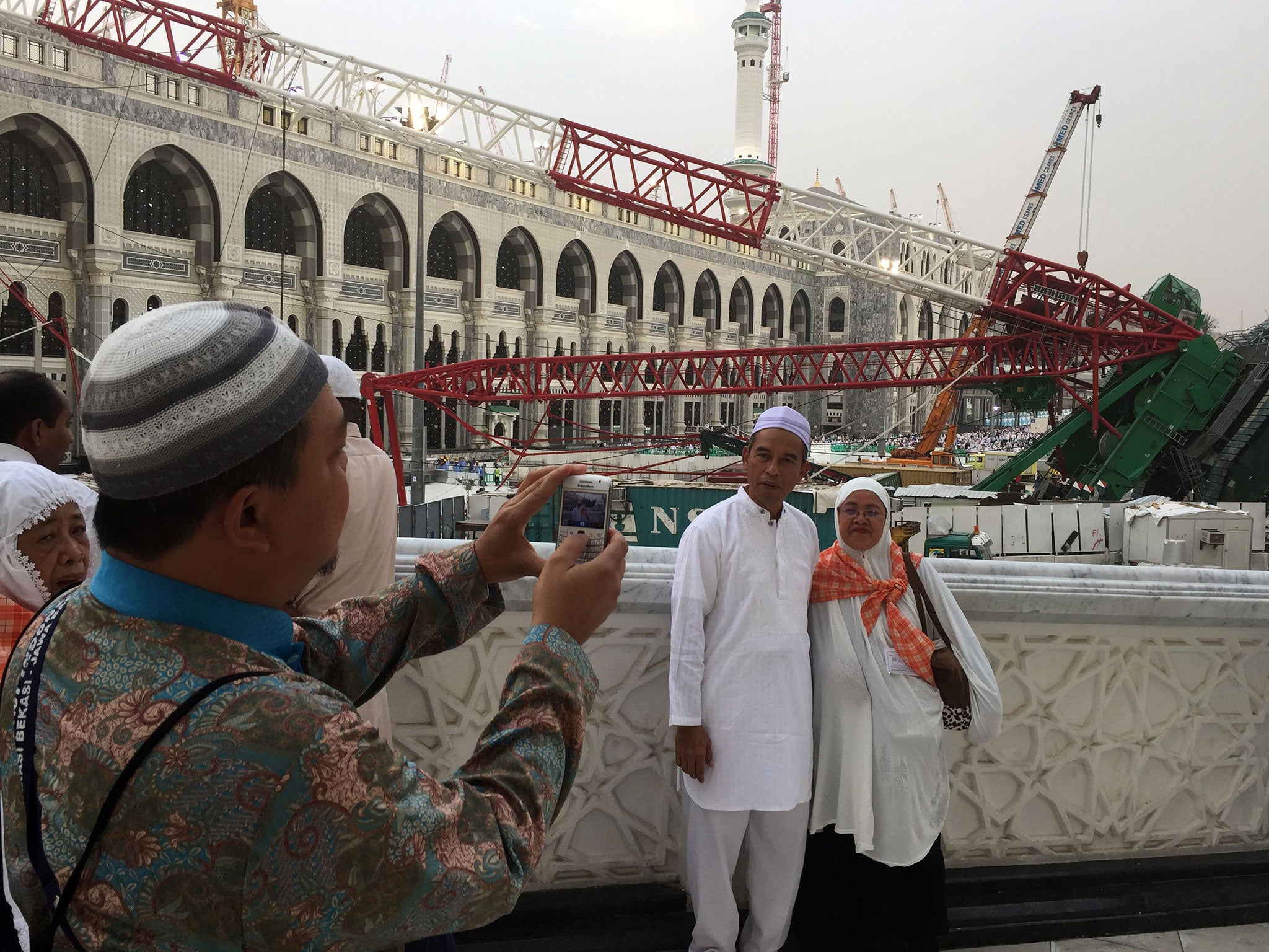 Muslim pilgrims take pictures in front of a crane that collapsed at the Grand Mosque in Saudi Arabia's holy Muslim city of Mecca