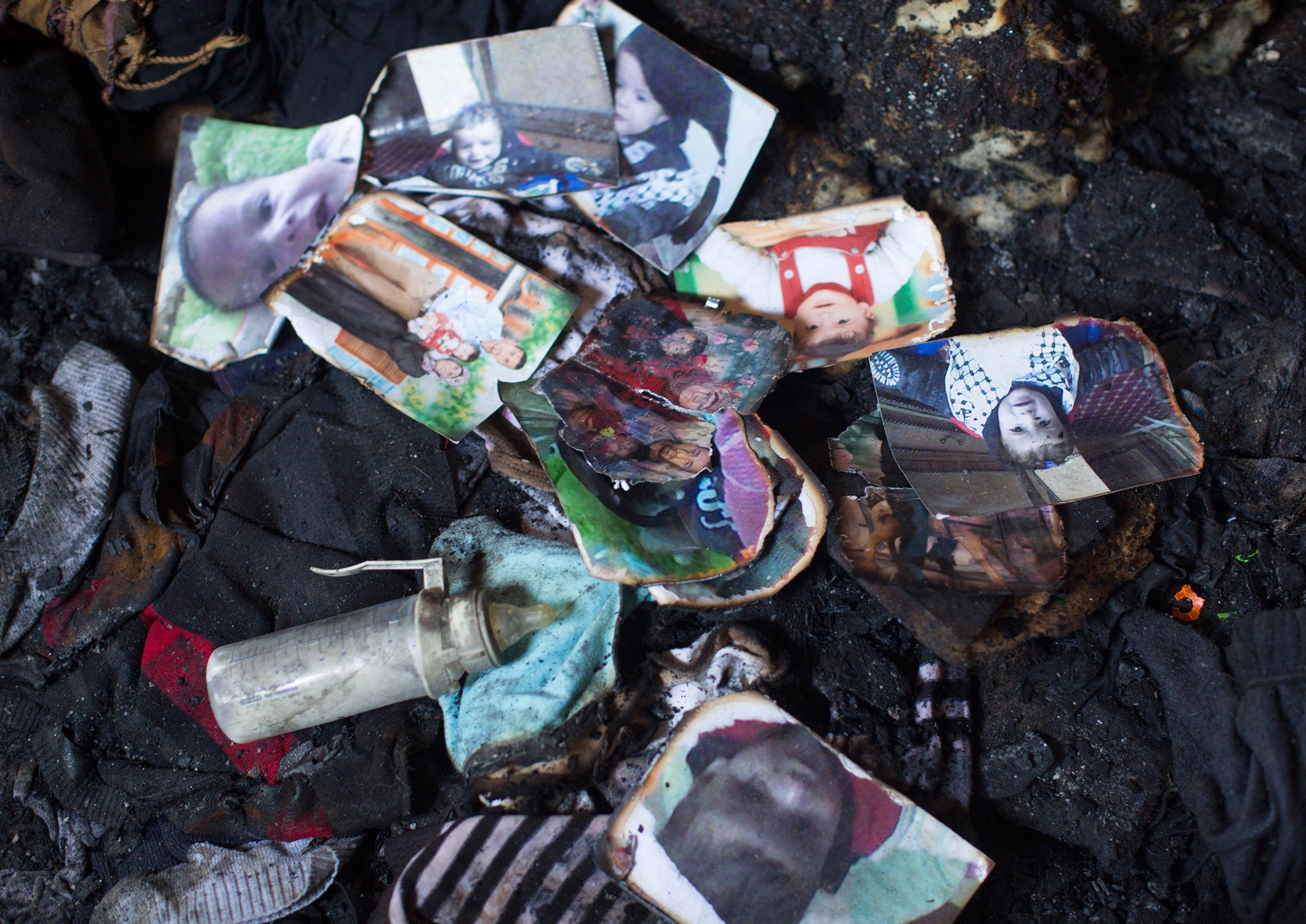 Photos of the Dawabsheh family lie in a burnt pile among the ruins of their house