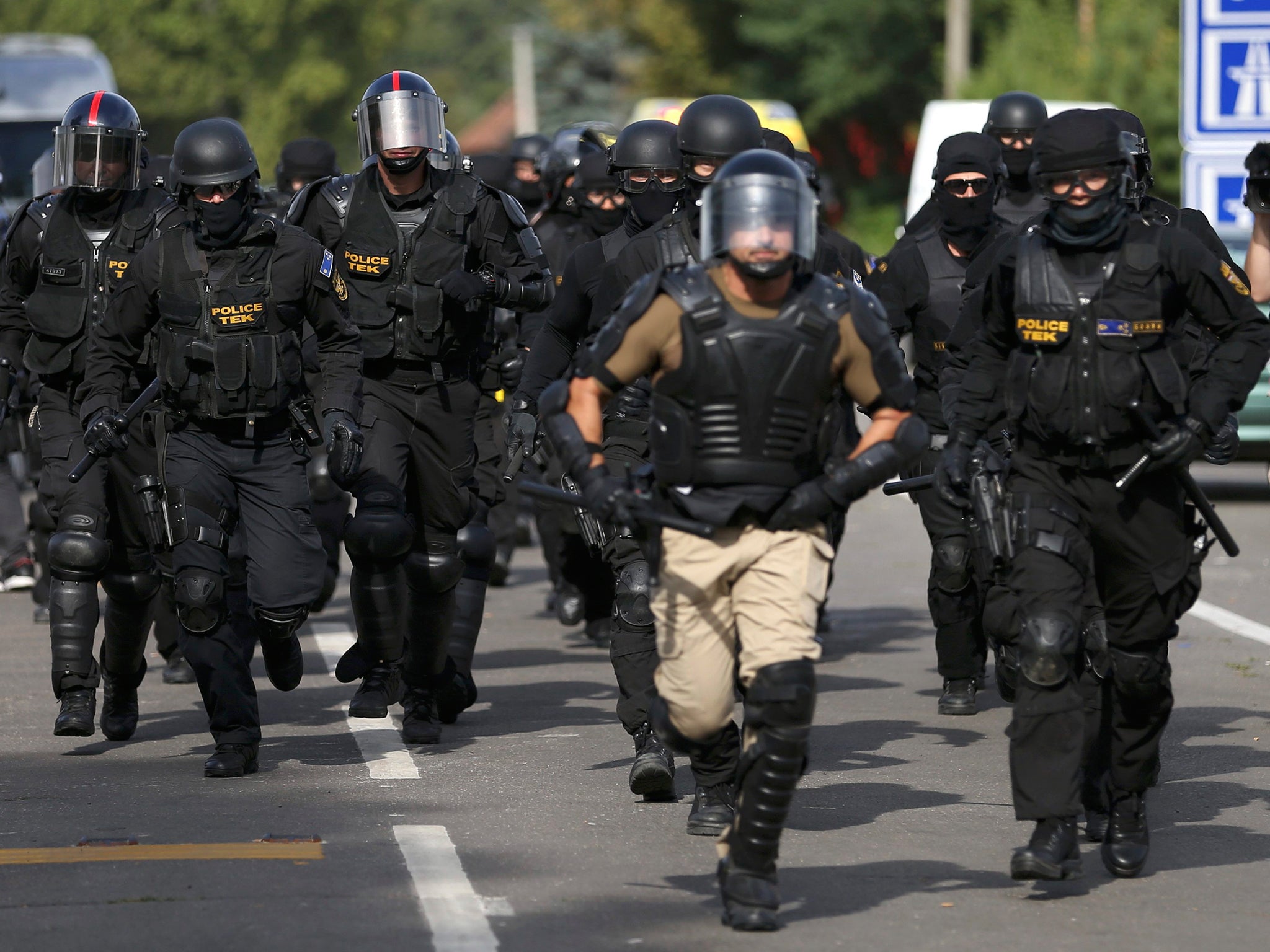 Hungarian riot policemen run as they are deployed at the border crossing with Serbia in Roszke