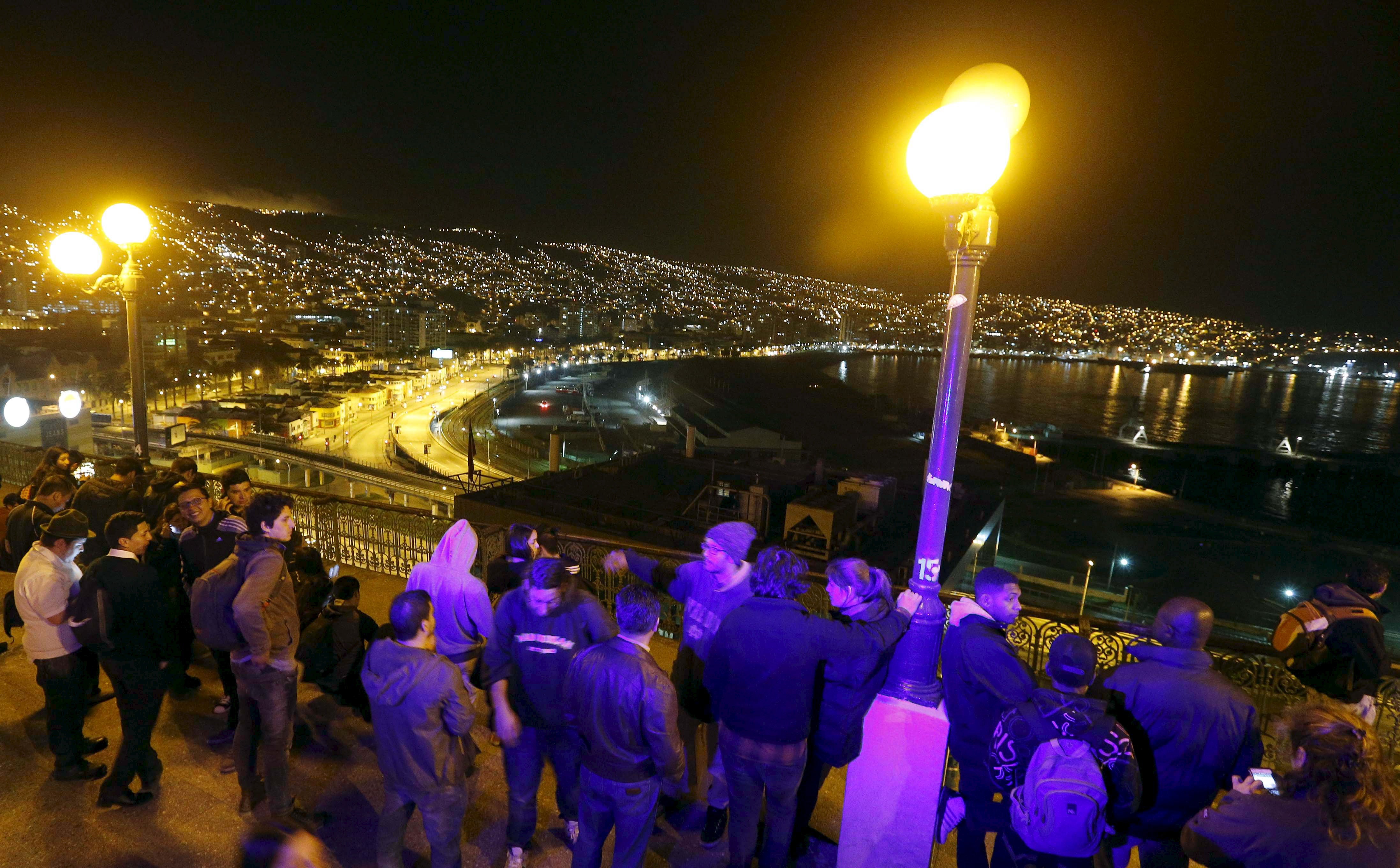 People stand and watch the ocean on Cerro Baron hill