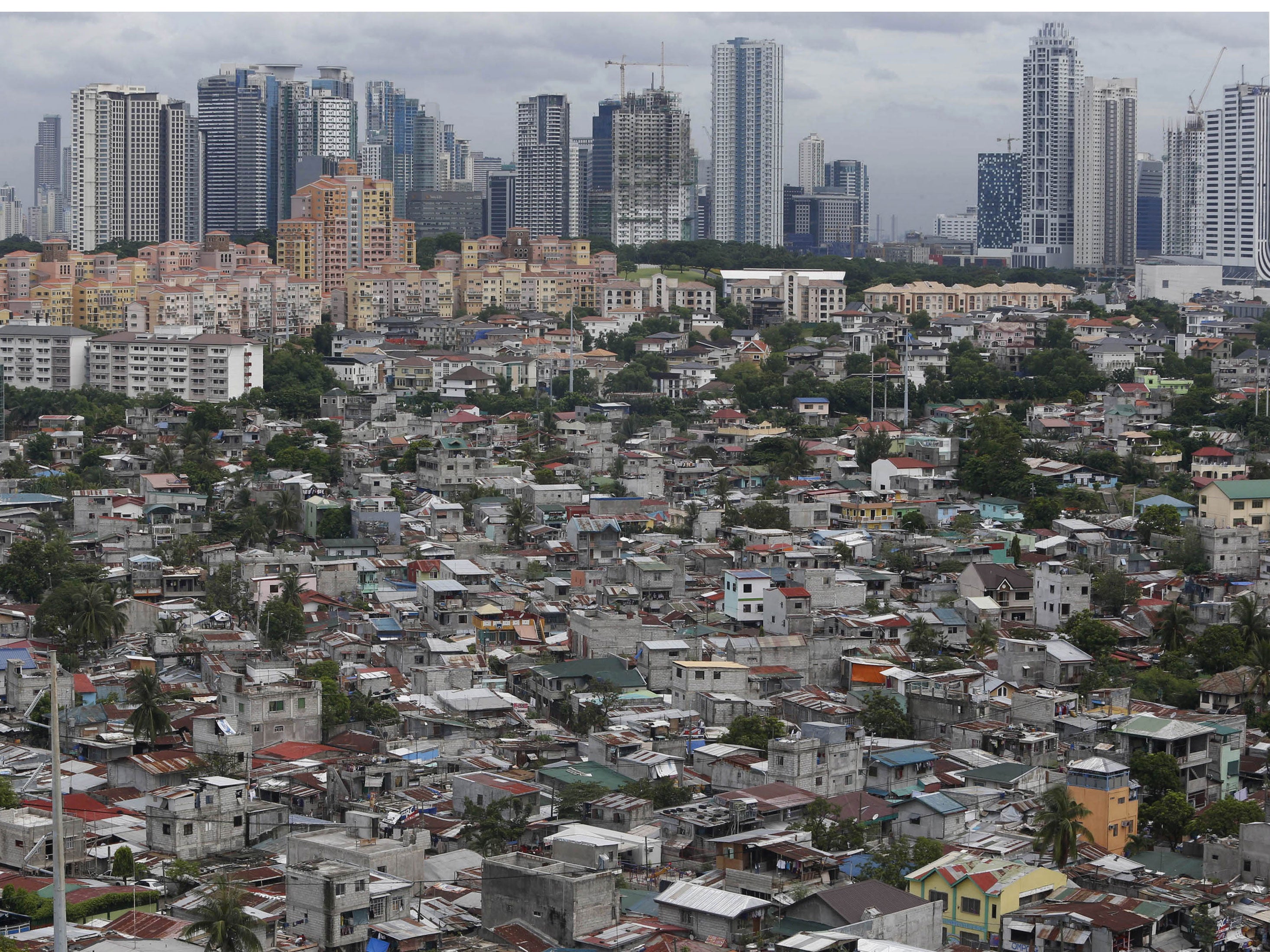 A poor residential district and squatter colonies are overlooked by high rise residential and commercial buildings in Taguig, Metro Manila July 4, 2013