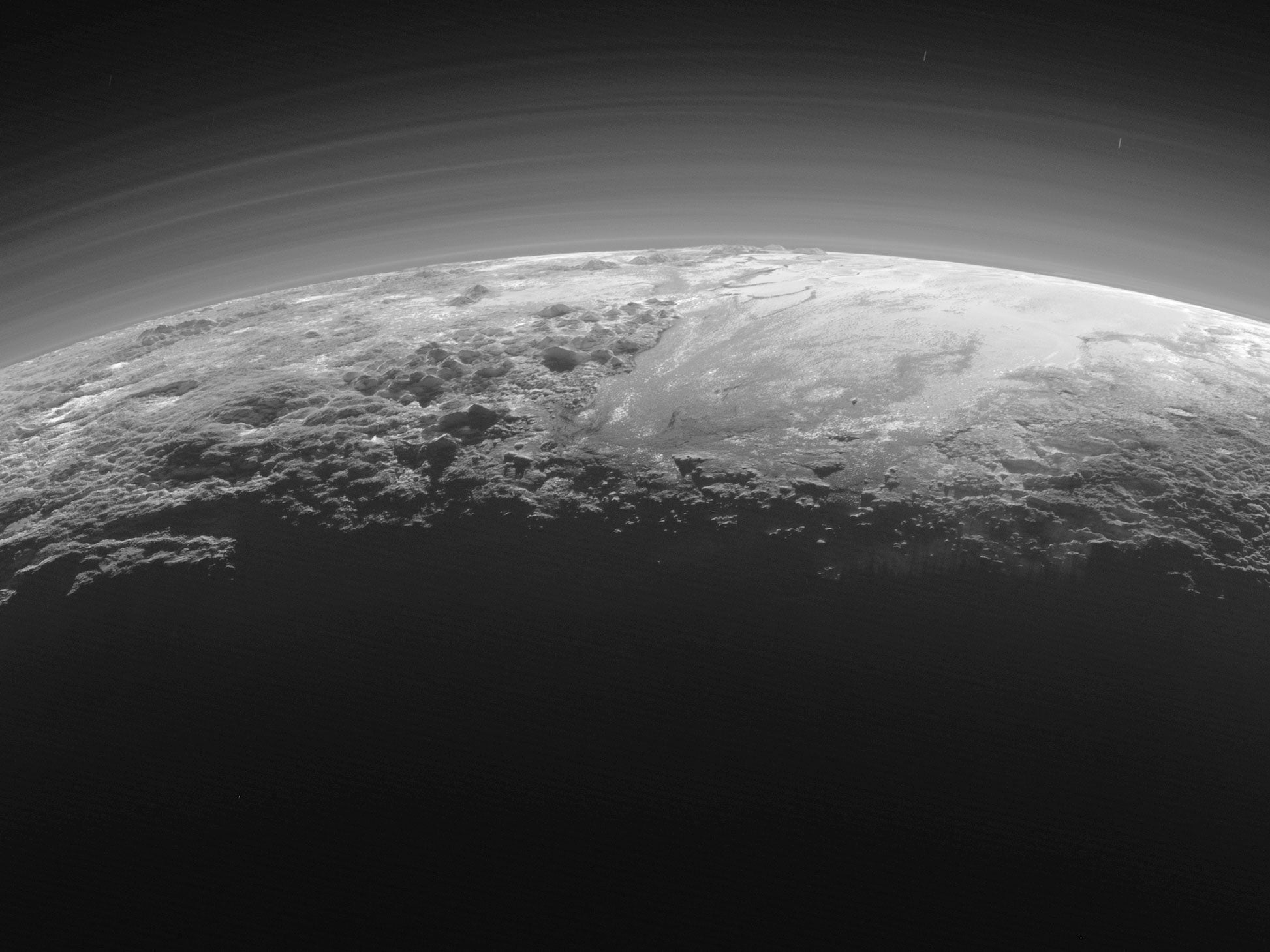 The smooth expanse of Sputnik Planum (right) is flanked to the west by mountains up to 11,000 feet high, including Norgay Montes and Hillary Montes. To the right, rougher terrain is cut by apparent glaciers.