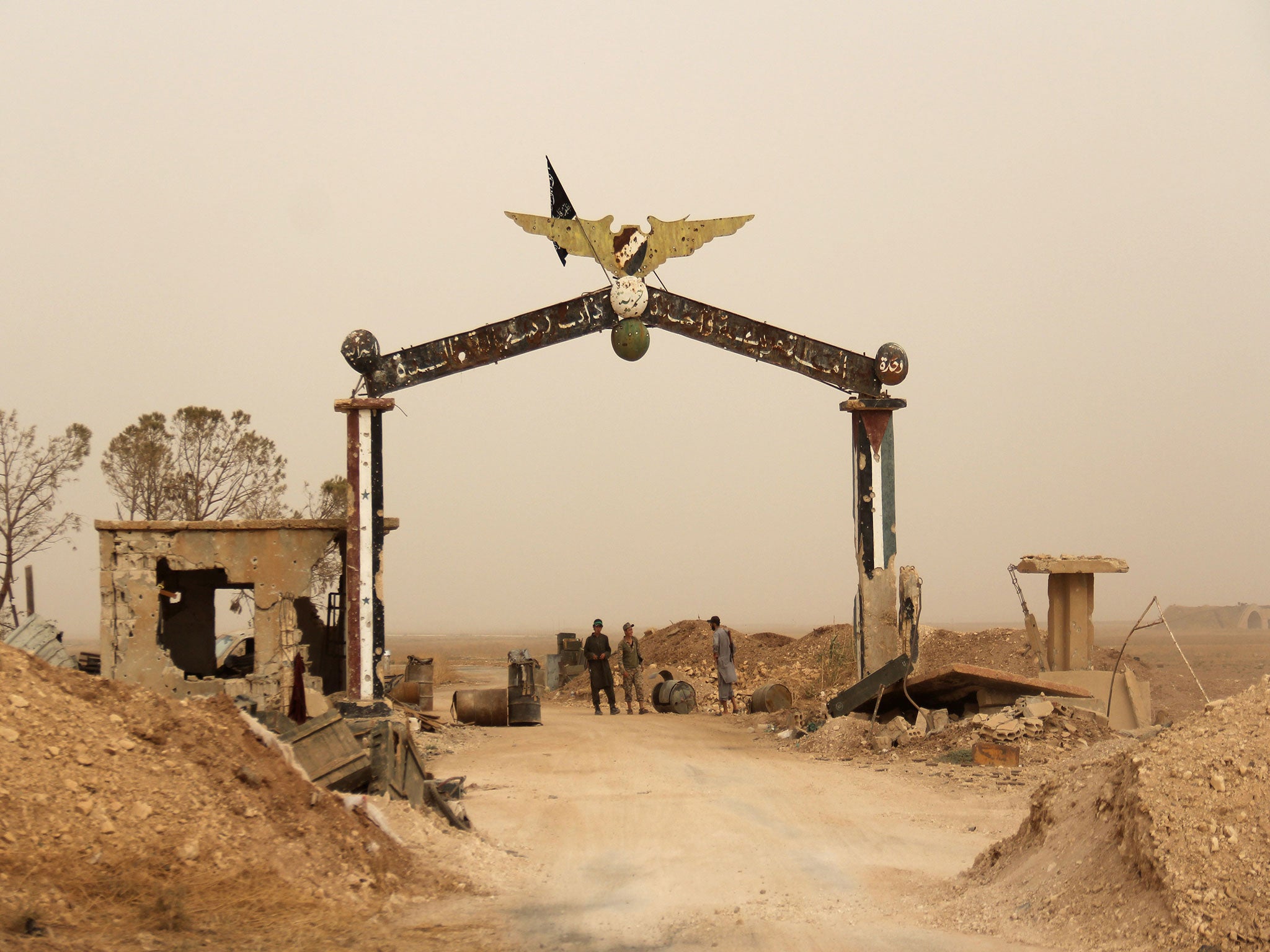 Members of Al-Qaeda's Syrian affiliate and its allies stand at the entrance of the Abu Duhur military airport