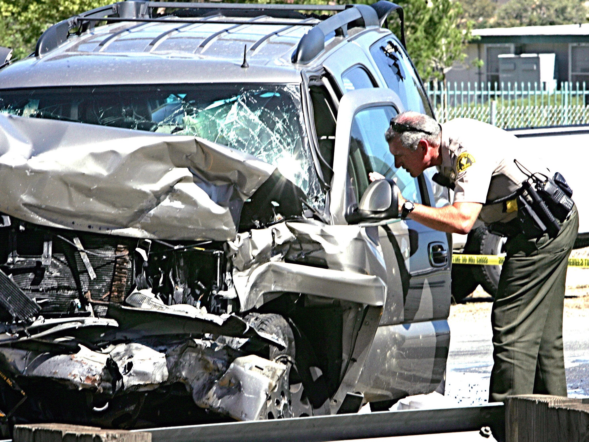 A deputy checks an SUV involved in a crash on Interstate 215 at the Little League Drive freeway overpass in San Bernardino, California