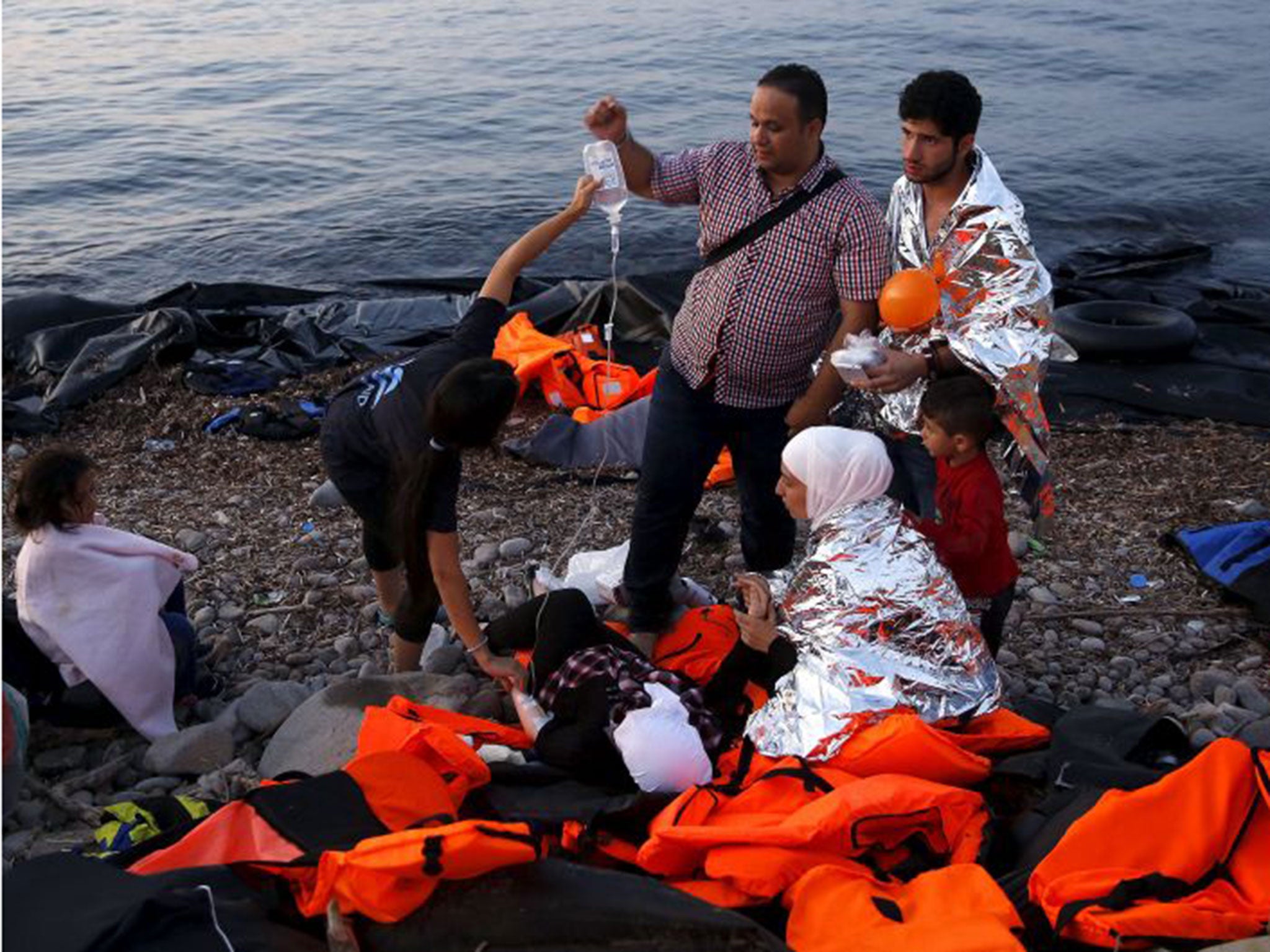 Volunteers provide medical help to a pregnant Syrian refugee woman shortly after she arrived on Lesbos