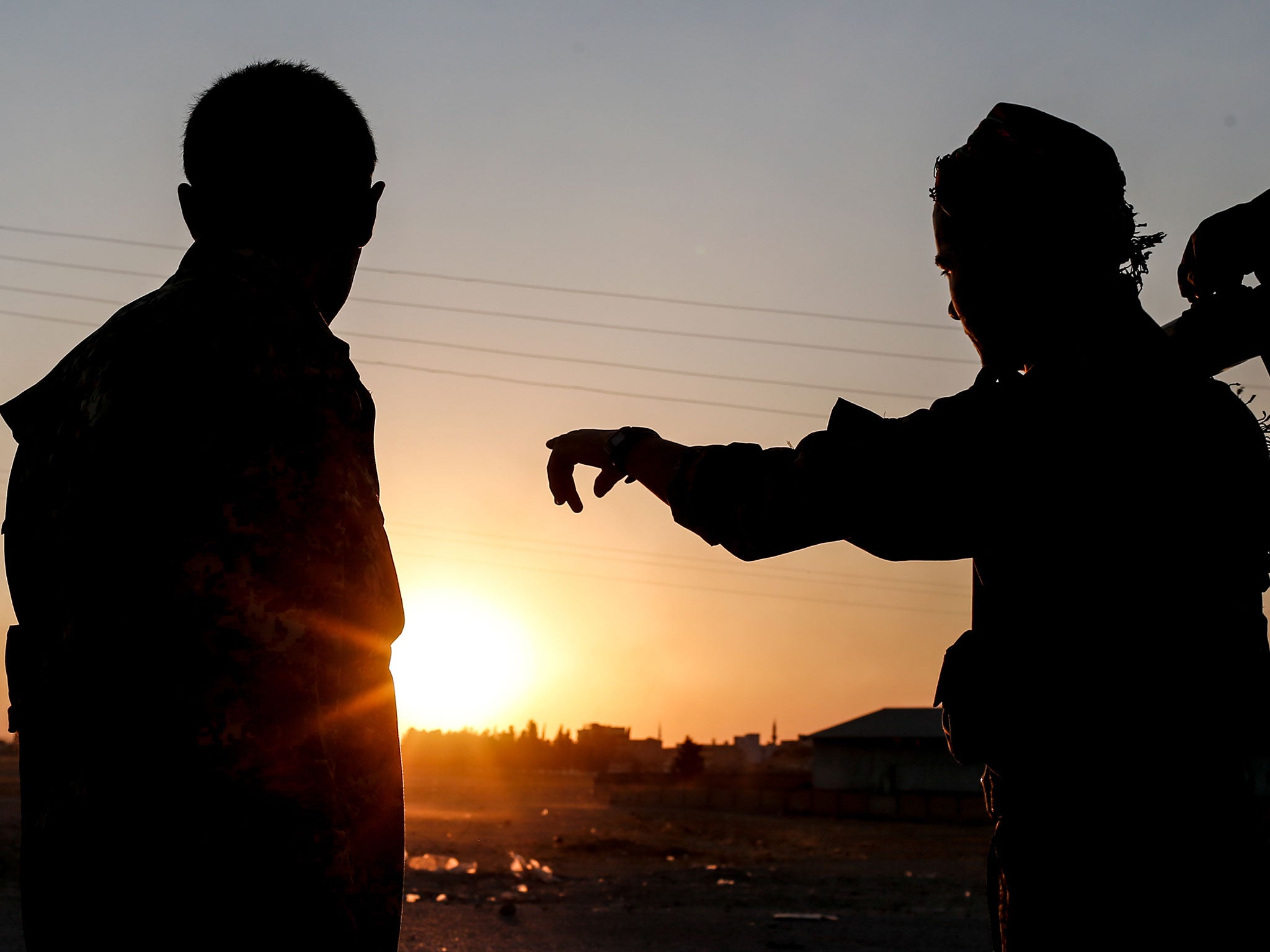 Members of the Kurdish People’s Protection Units (YPG) stand guard near the Tel Abyad border gate in northern Syria