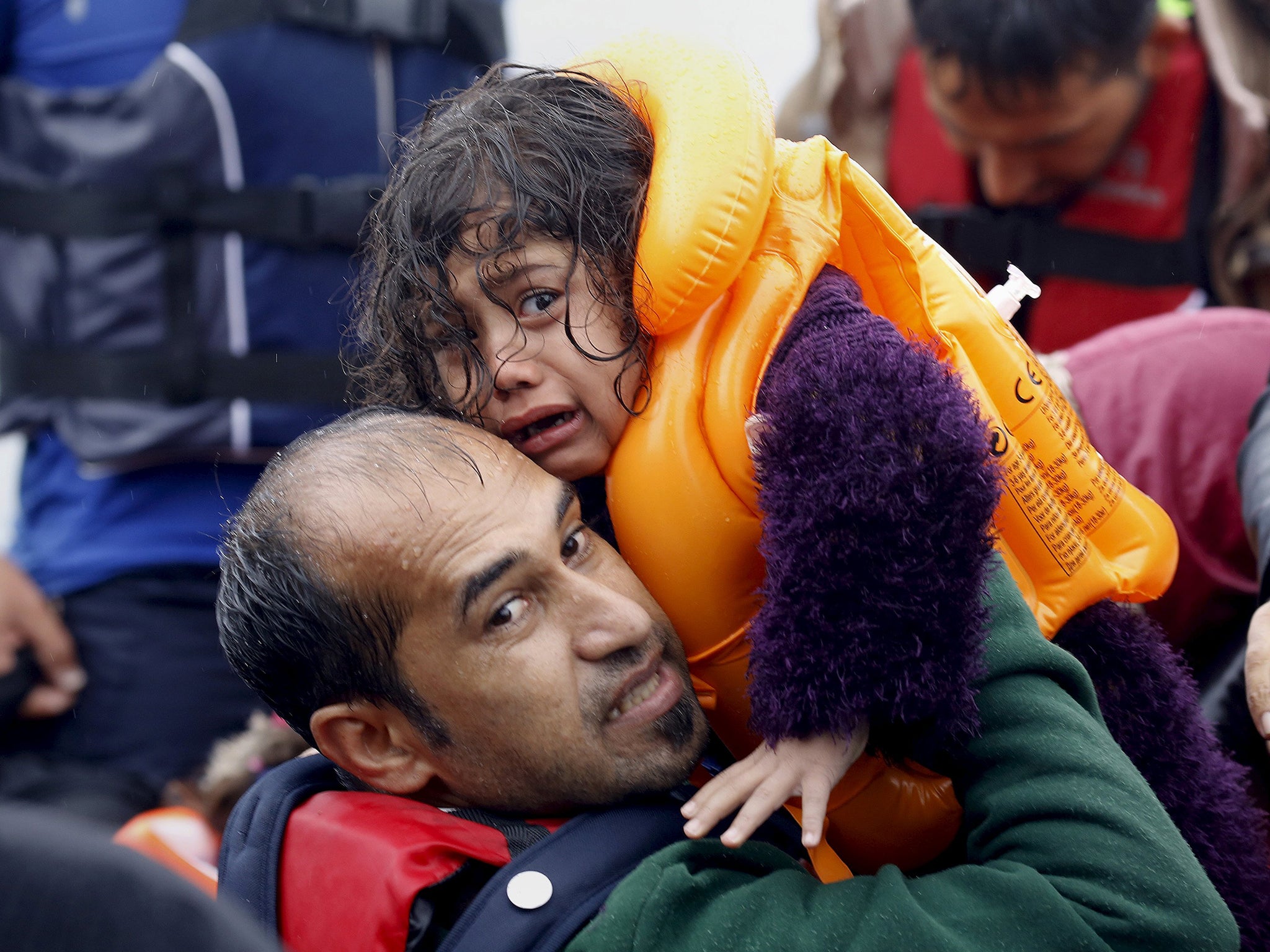 A Syrian refugee lifts his daughter from an overcrowded dinghy after crossing part of the Aegean Sea from Turkey to the Greek island of Lesbos