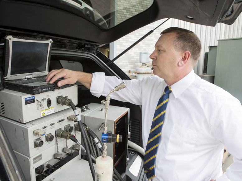Daniel Carder, the interim director of West Virginia University's Center for Alternative Fuels, Engines and Emissions in Morgantown, West Virginia is shown with a vehicle that has a testing equipment installed, in this undated West Virginia University pho