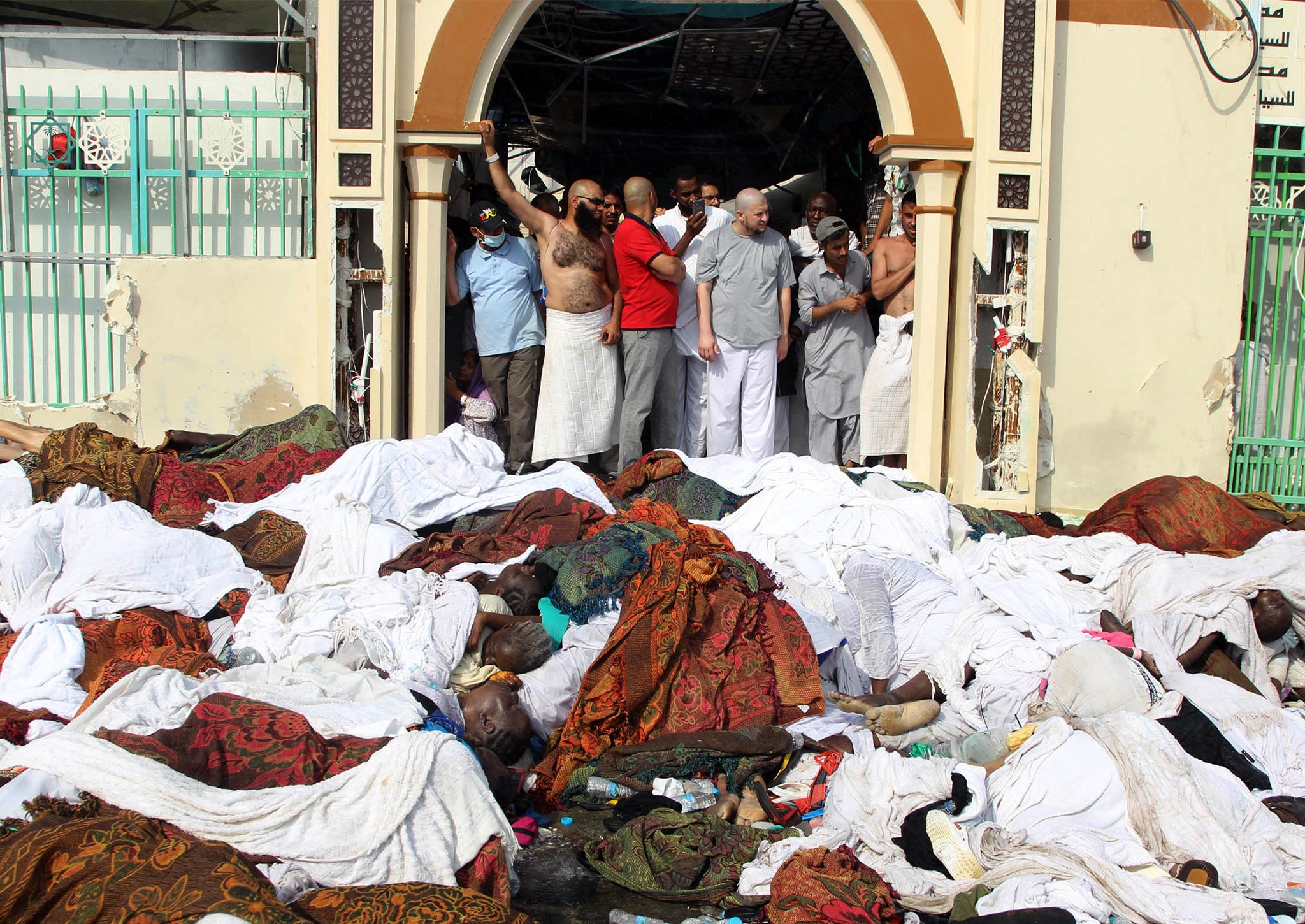 Saudi emergency personnel stand near bodies of Hajj pilgrims at the site where at least 717 were killed and hundreds wounded in a stampede in Mina, near the holy city of Mecca, at the annual hajj in Saudi Arabia on September 24, 2015.