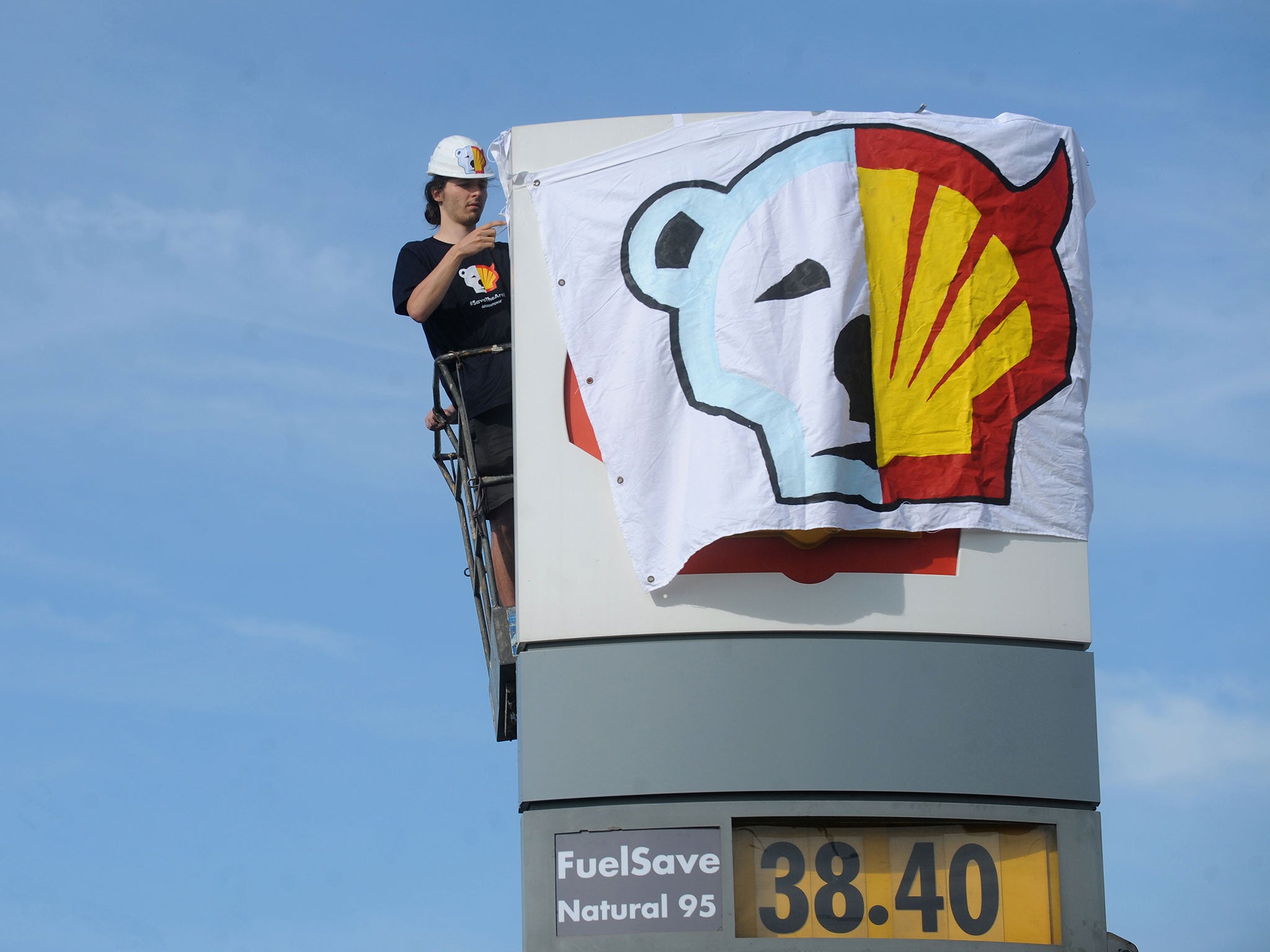 A Greenpeace activist covers the logo of the Shell oil company to protest on May 10, 2012 against the heading of the an icebreaker for Shell's Arctic oil drilling project