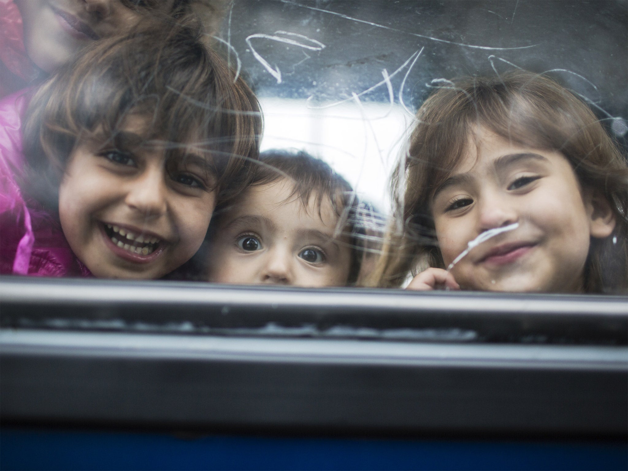 Refugee children who have crossed from Serbia waiting for a bus in Hungary to deliver them to a compound where they are processed