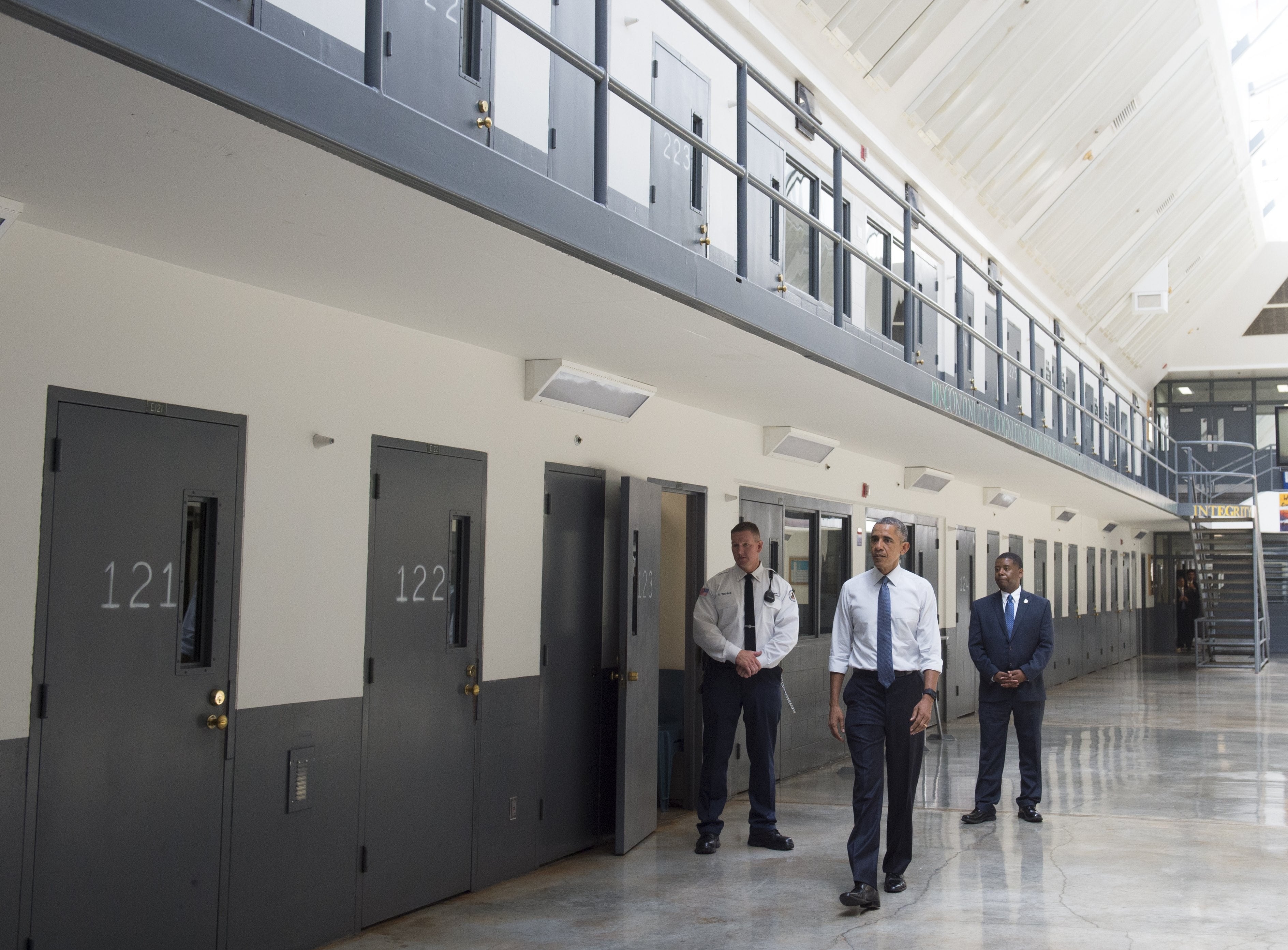 Barack Obama, alongside officer Ronald Warlick, left, and Charles Samuels, right, Bureau of Prisons Director, tours a cell block at the El Reno Federal Correctional Institution in Oklahoma.