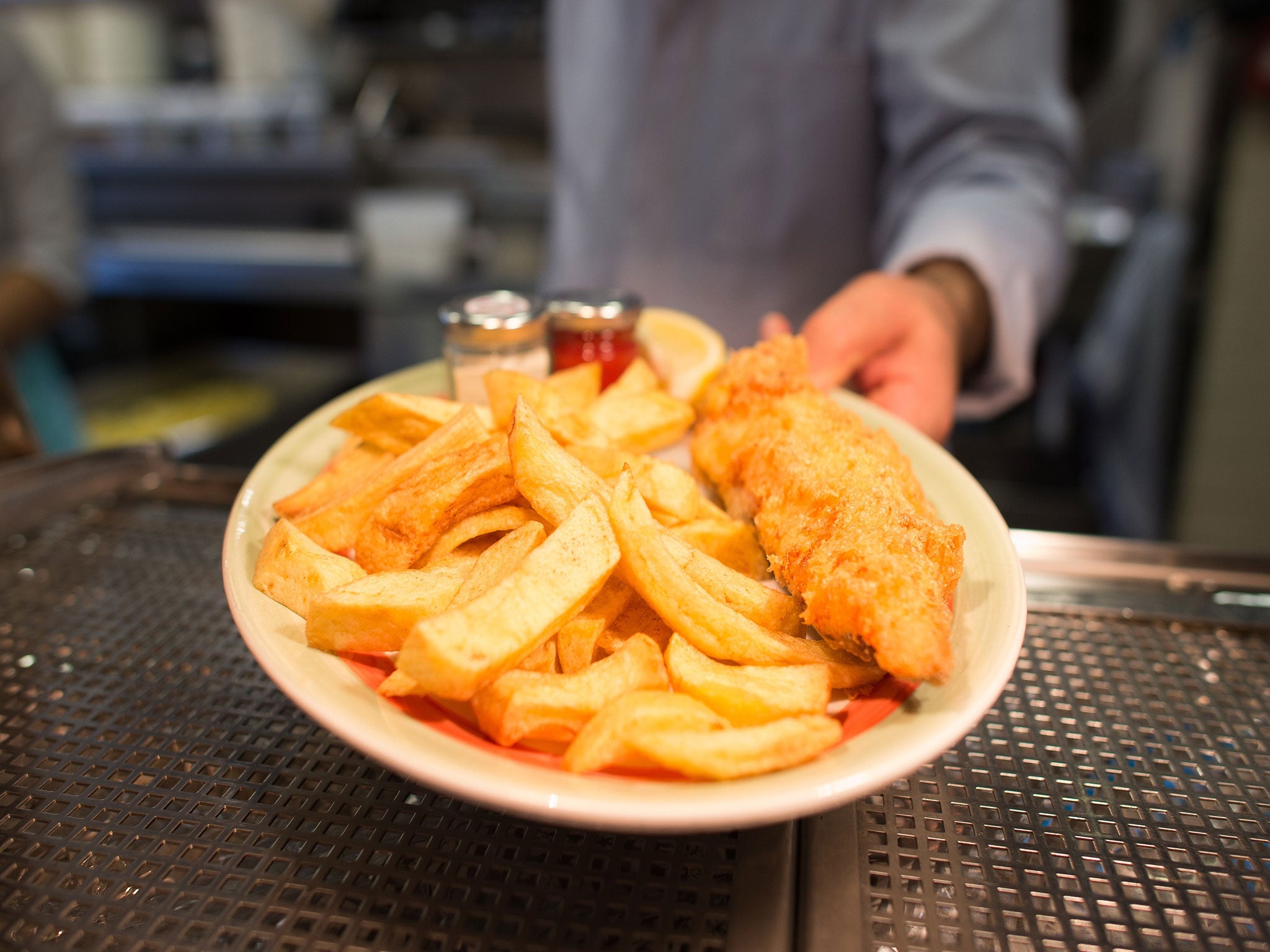 A chef with a plate of fish and chips at Poppies fish and chip restaurant in east London