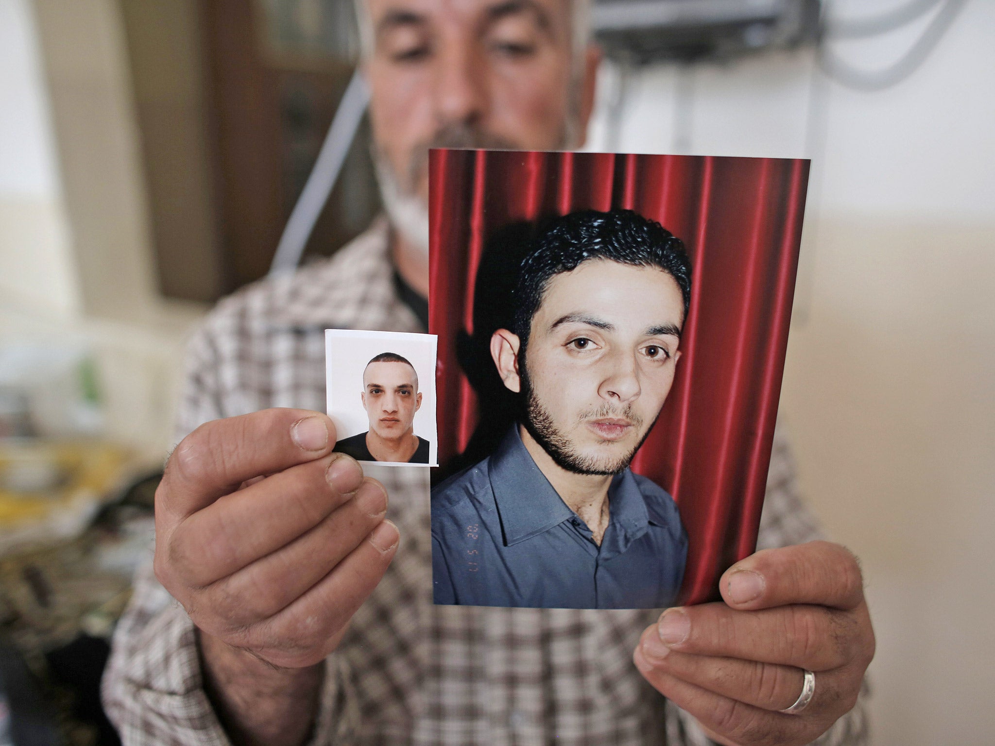 &#13;
A relative of Palestinian cousins Uday, left, and Ghassan Abu Jamal, shows their portraits at the family's residence last November (Getty)&#13;