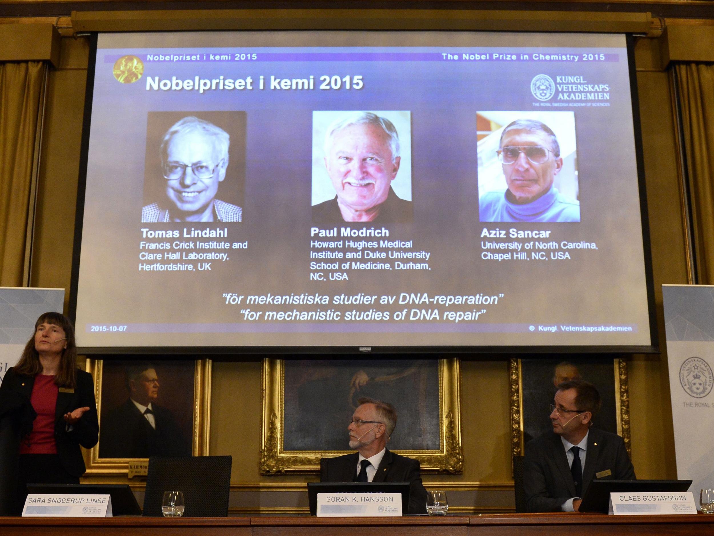 Members of the Nobel committee for chemistry sit in front of a screen displaying the portraits of the winners of the Nobel Prize in Chemistry 2015 (L-R) Sweden's Tomas Lindahl, Paul Modrich of US and Turkish-American Aziz Sancar during a press conference on October 7, 2015 at the Royal Swedish Academy of Sciences in Stockholm