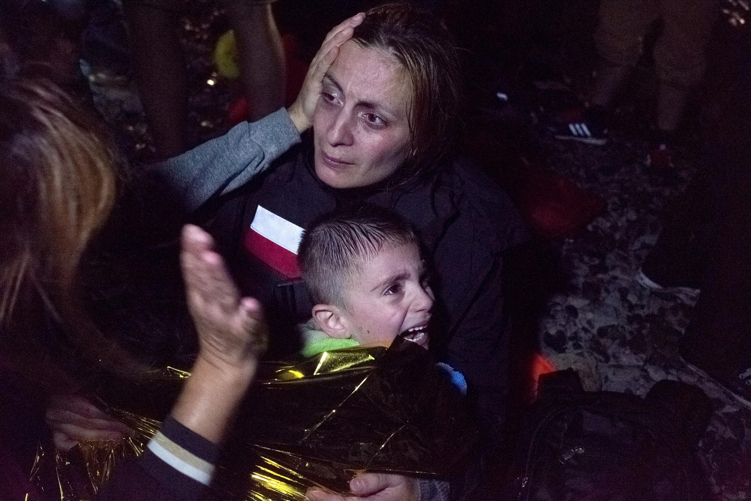 A Syrian refugee holds her child as she is comforted by a volunteer following her arrival on an overcrowded dinghy on the Greek island of Lesbos