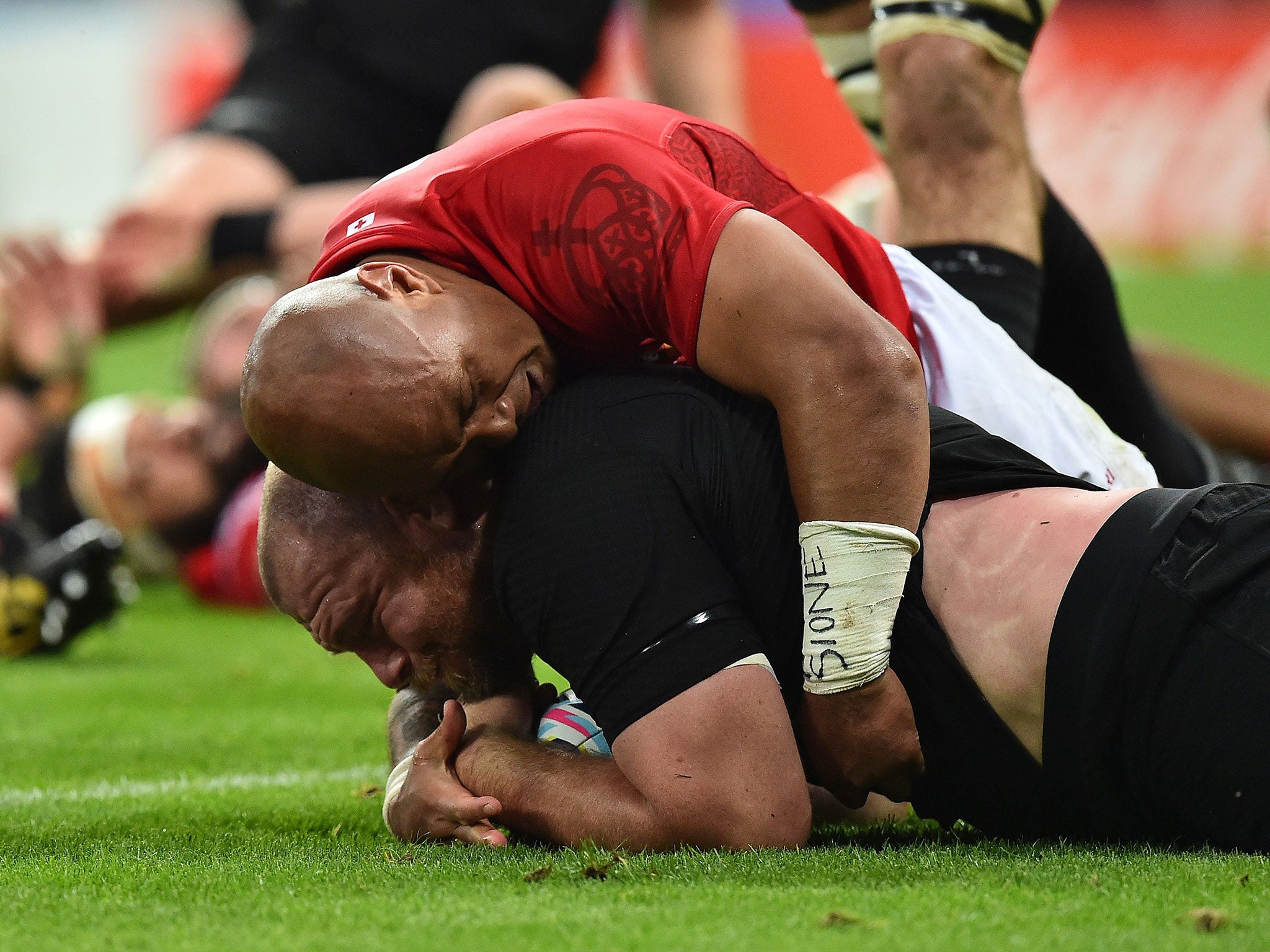 Tony Woodcock scores for New Zealand despite the tackle from Tonga's Nili Latu