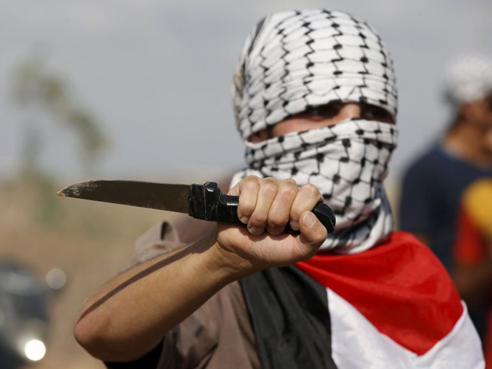 A masked Palestinian protester holds a knife during a protest near the Israeli border fence in northeast Gaza