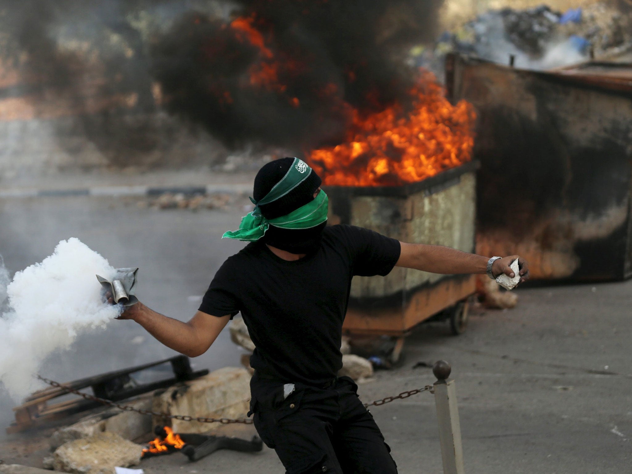 A Palestinian protester returns a tear gas canister fired by Israeli troops during clashes near the Jewish settlement of Bet El, near Ramallah, on 10 October