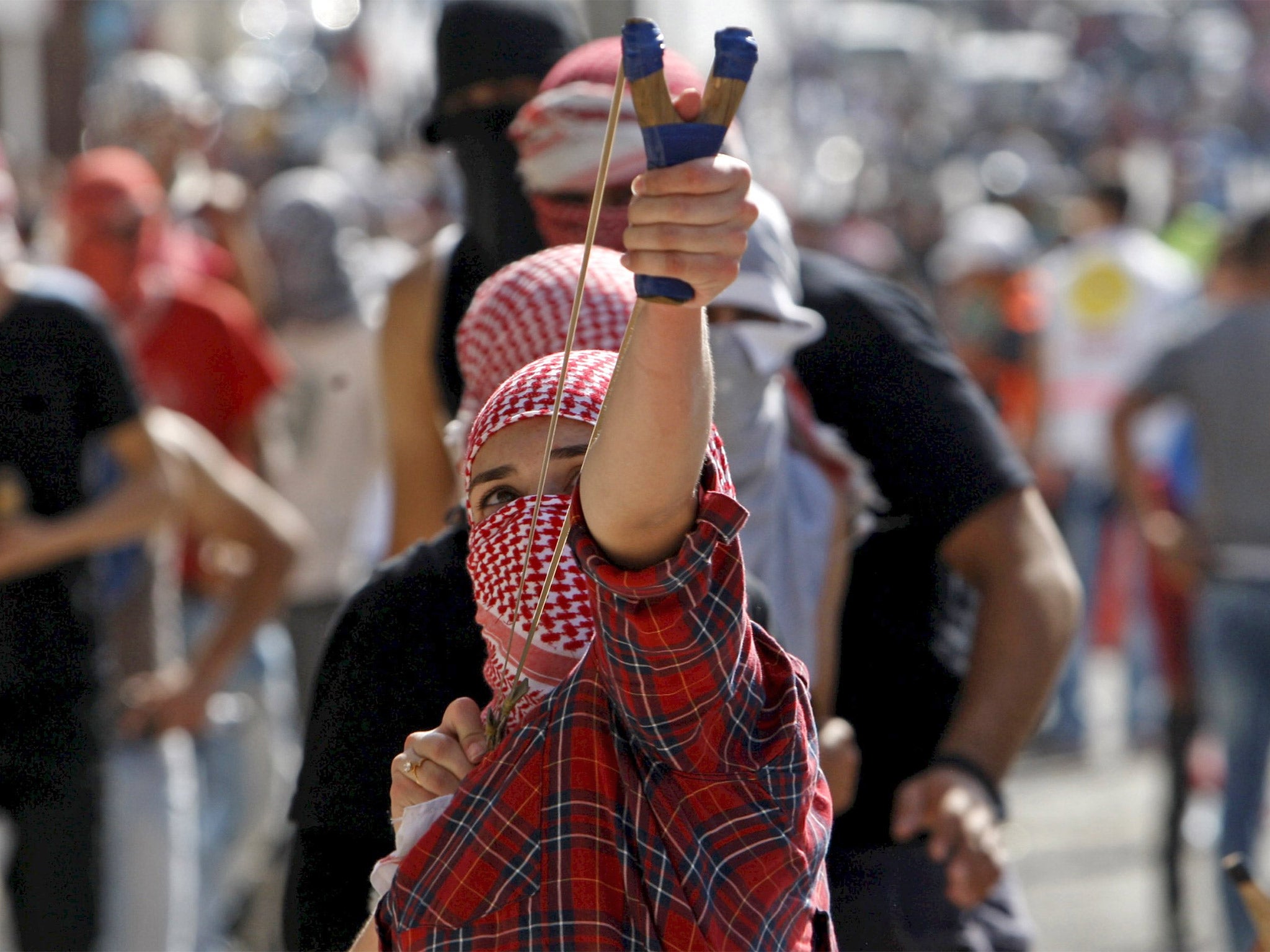 A Palestinian uses a slingshot to throw stones at Israeli troops during clashes in Bethlehem