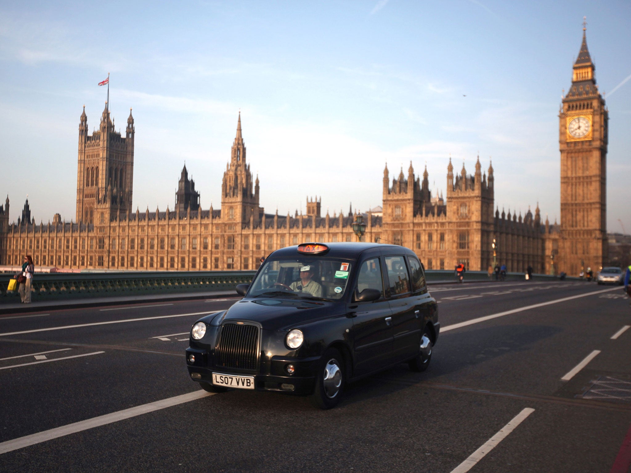 A black taxi cab makes its way over Westminster Bridge