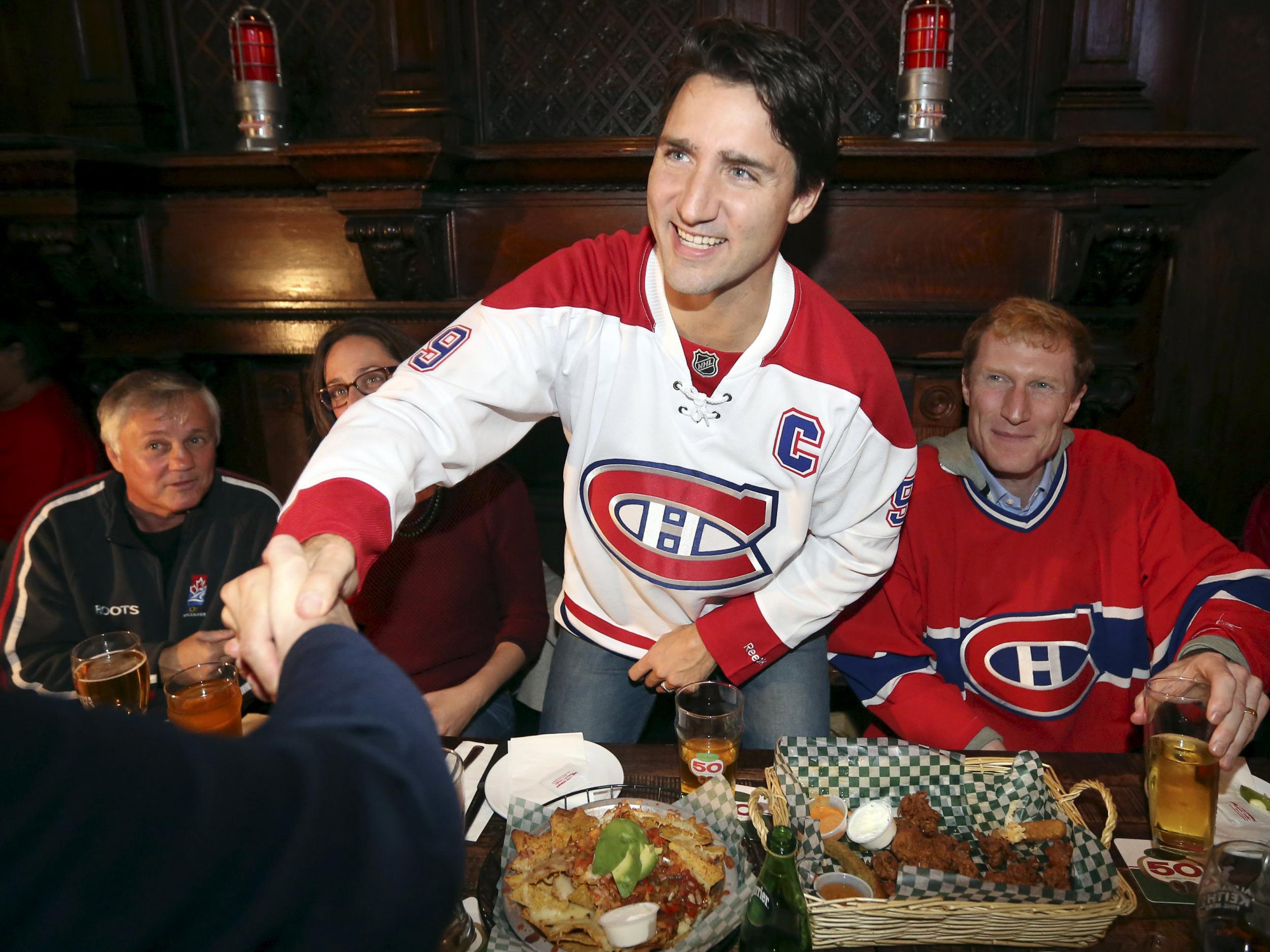 Liberal leader Justin Trudeau shakes hands while watching a Montreal Canadiens hockey game at a bar in Montreal, Quebec,