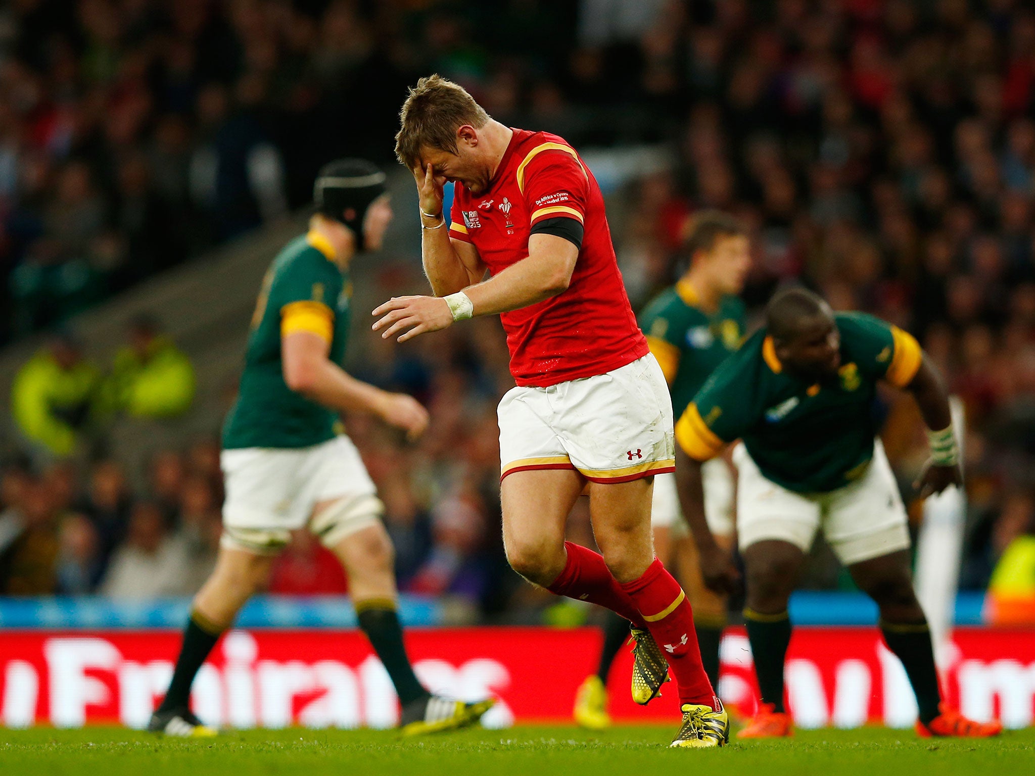 Wales fly-half Dan Biggar holds his head after being injured in a tackle