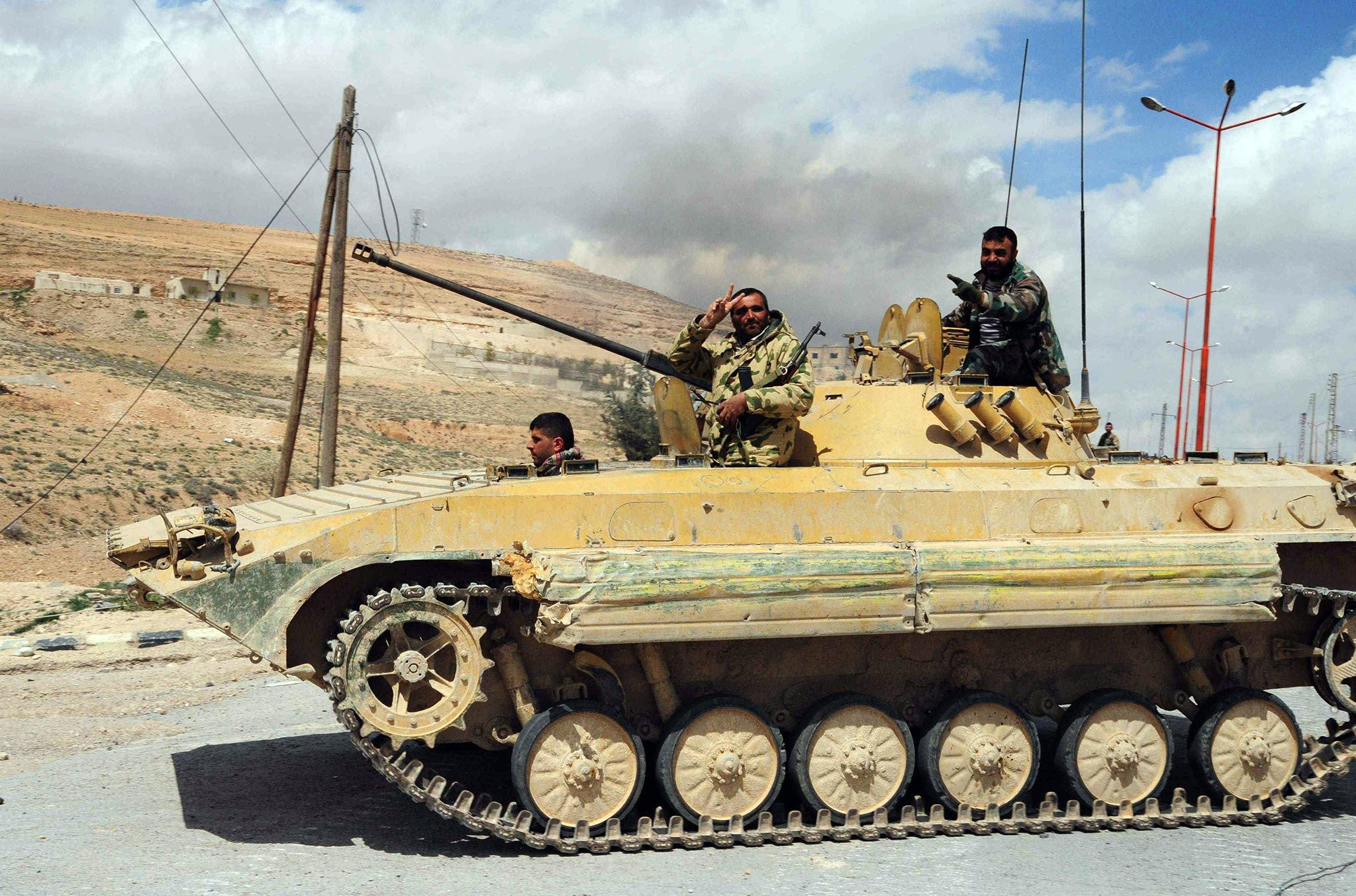 A Syrian army soldier flashes a 'V for victory' sign as his tank travels northeast of Damascus