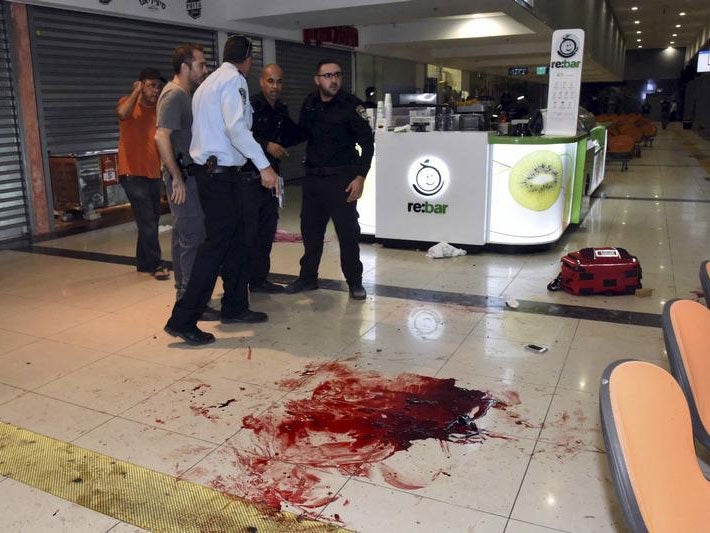 Israeli security personals stand next to blood on the floor, at the Beersheba central bus station