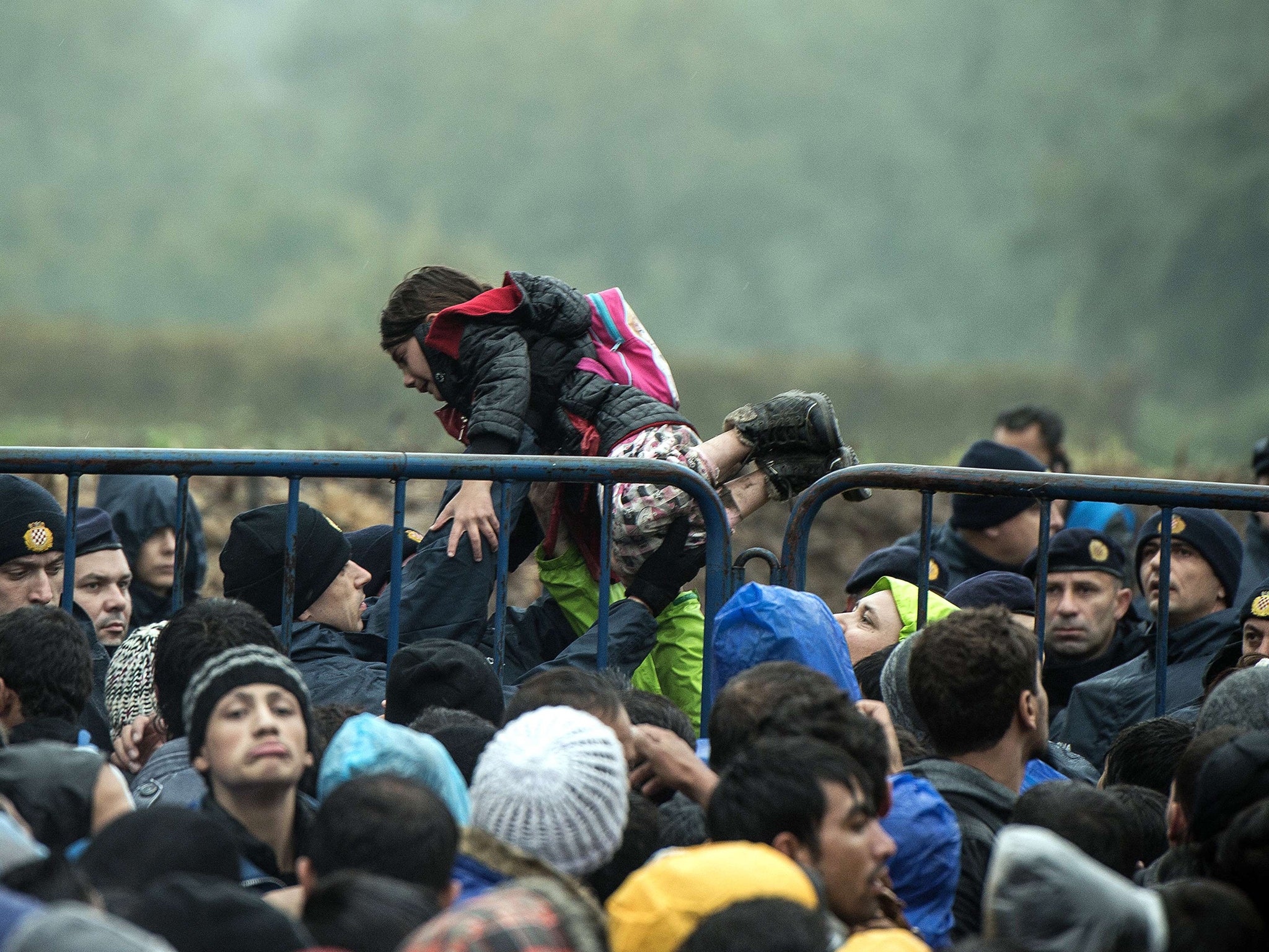 A child is held by a policeman as refugees wait to enter Croatia from Serbia