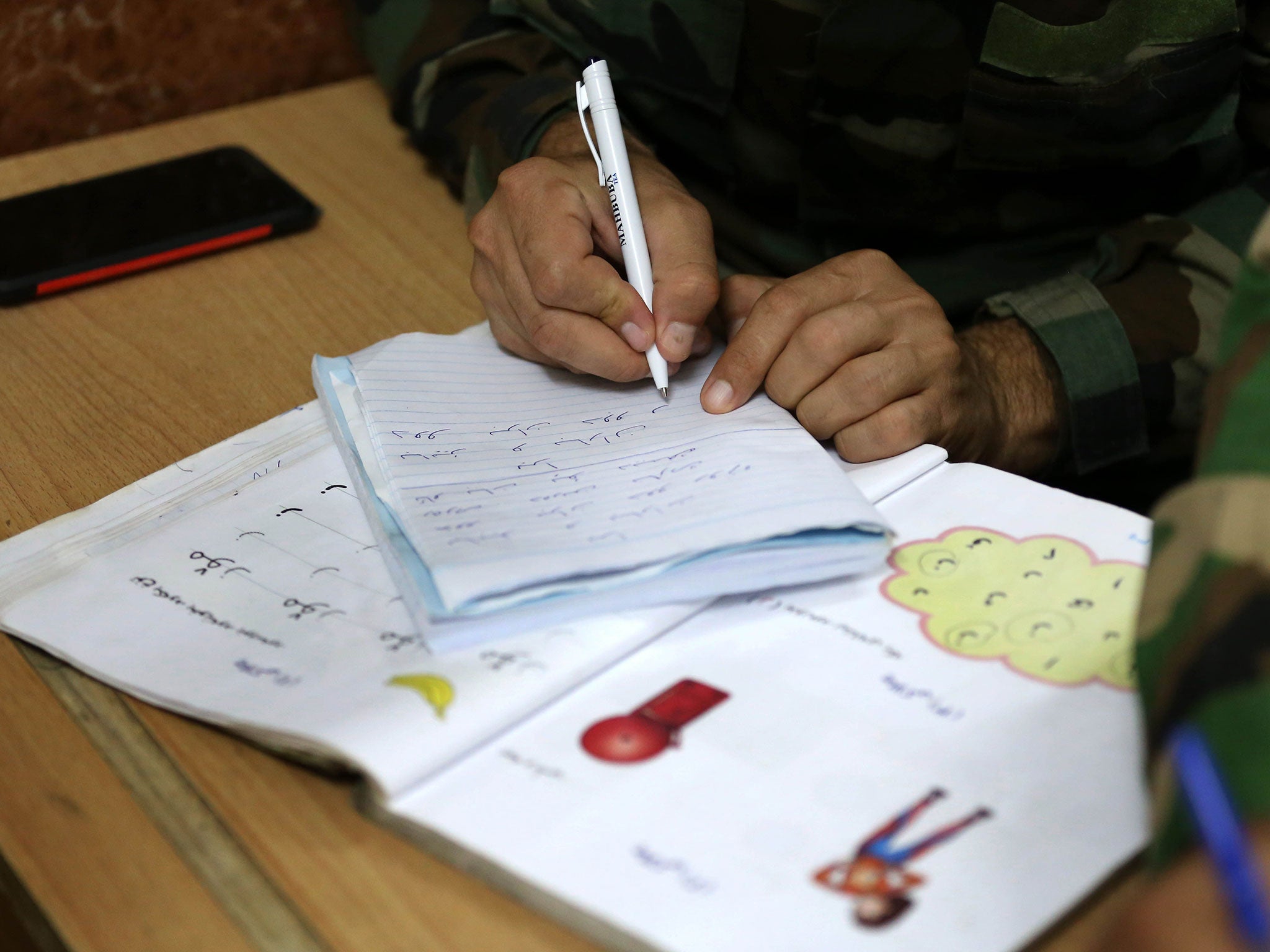 An Iraqi Kurdish Peshmerga fighter attends a night school in Iraq. The location of the classes is a closely guarded secret in order to protect the students