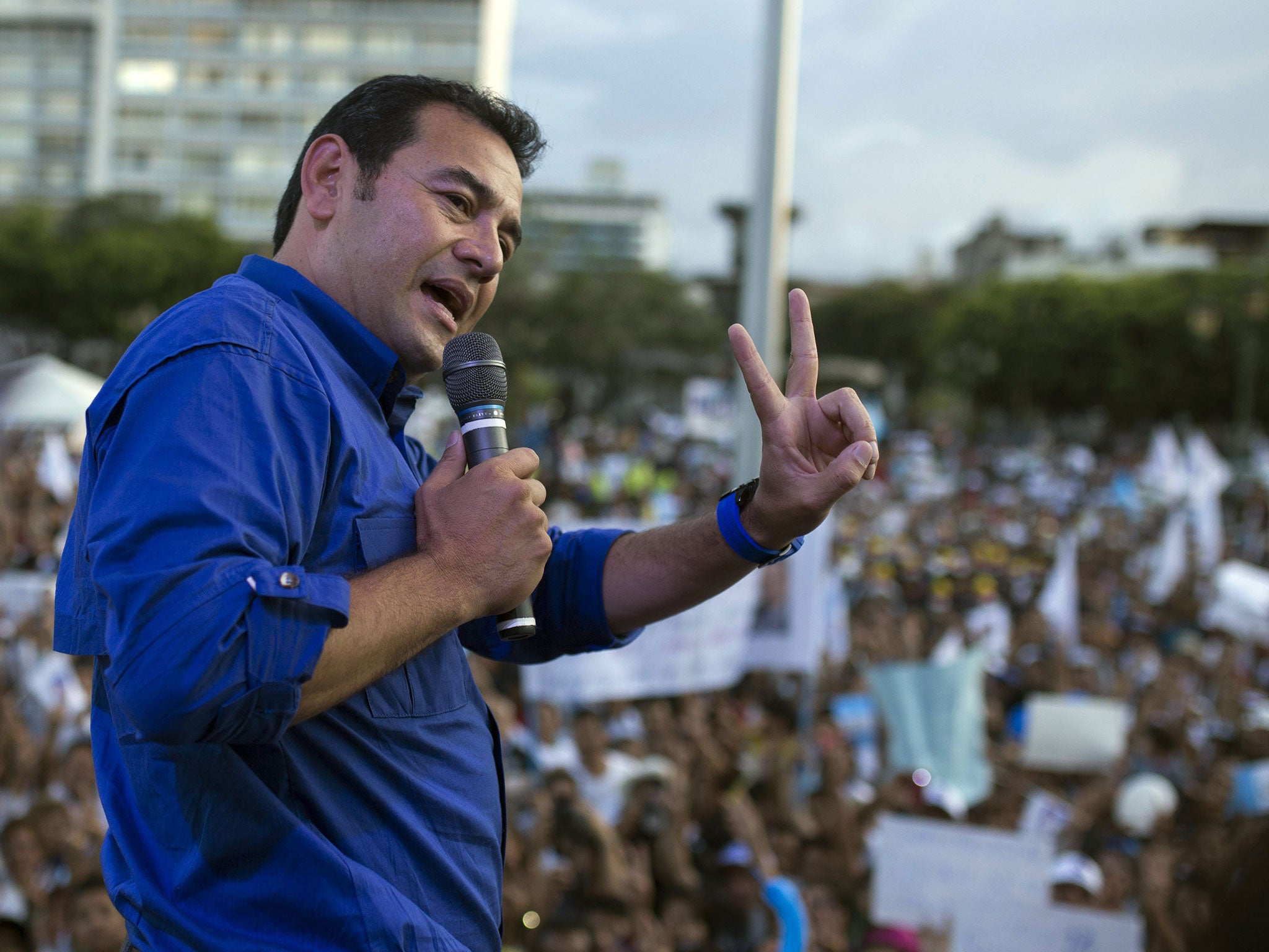 In this Thursday, Oct. 22, 2015 photo, Jimmy Morales, the National Front of Convergence party presidential candidate, gives a victory sign as he speaks to supporters during a campaign rally in Guatemala City