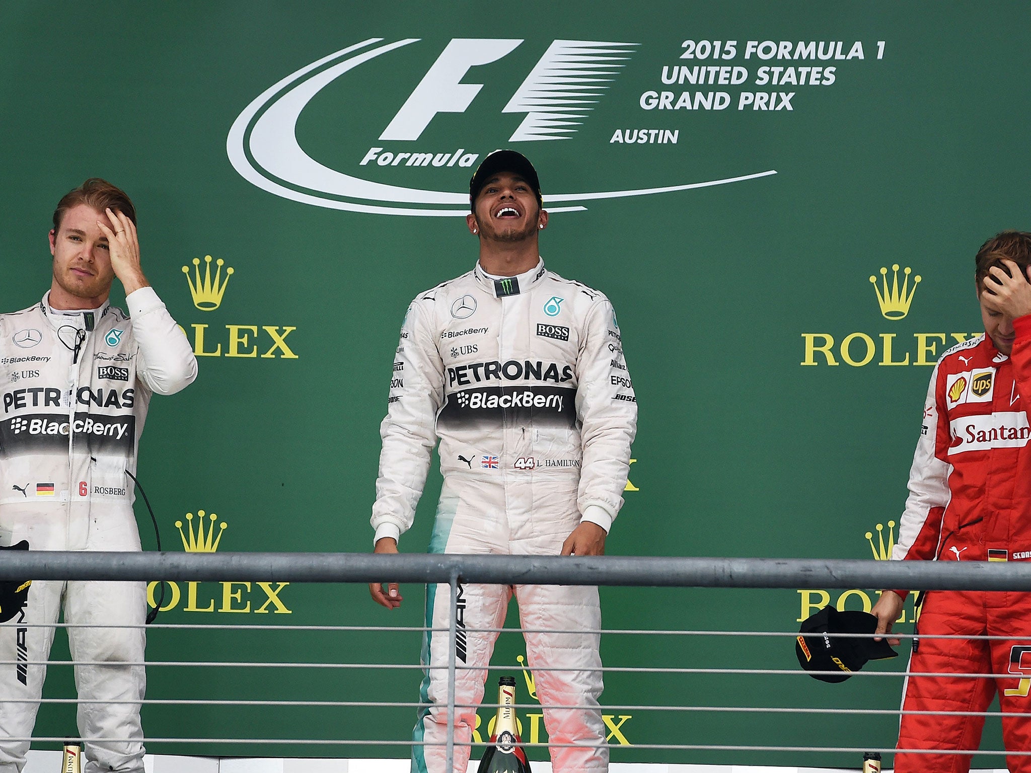 Lewis Hamilton celebrates on the podium as Nico Rosberg and Sebastian Vettel look dejected