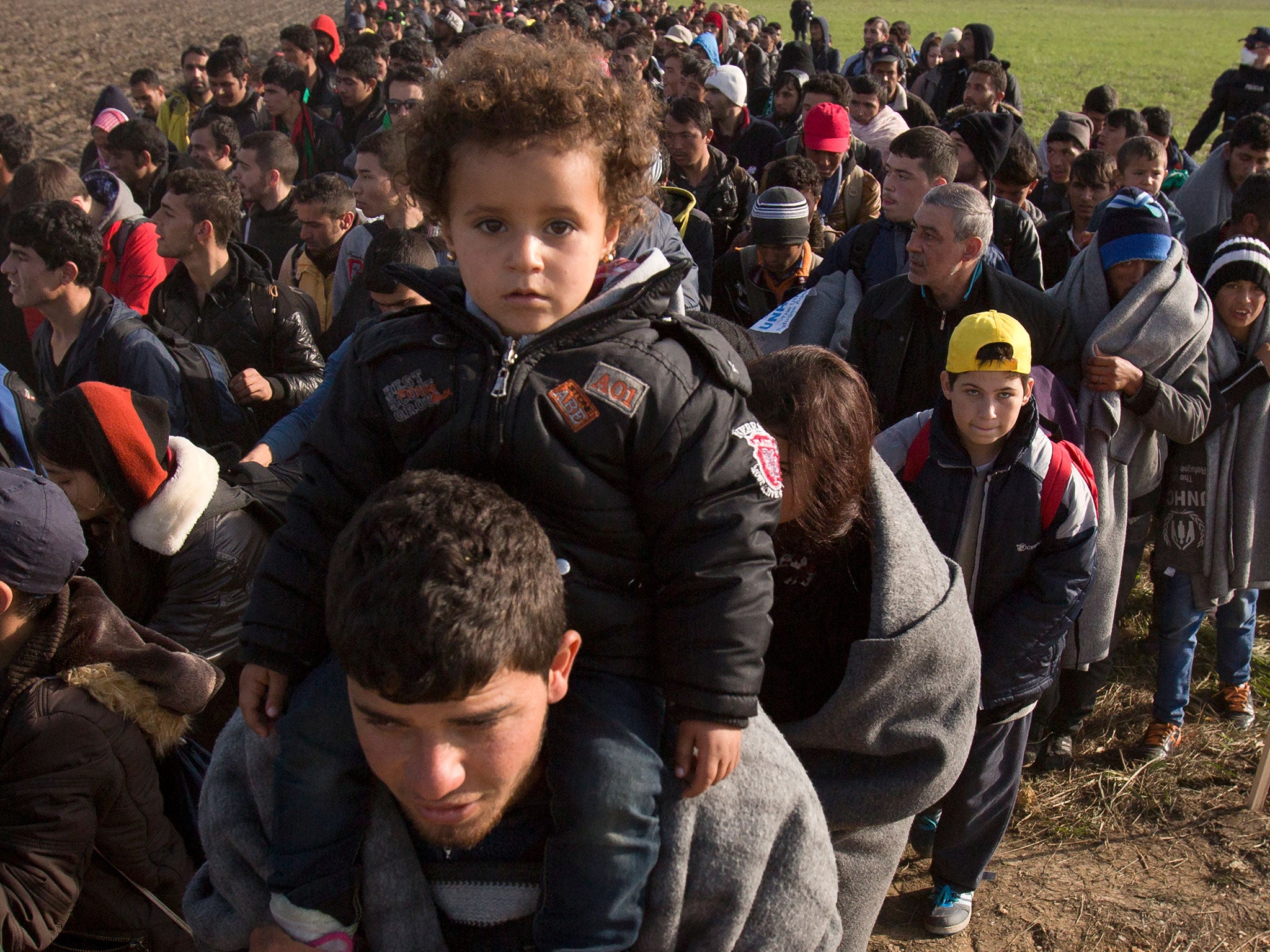 Refugees walk through fields in Romania after crossing from Croatia