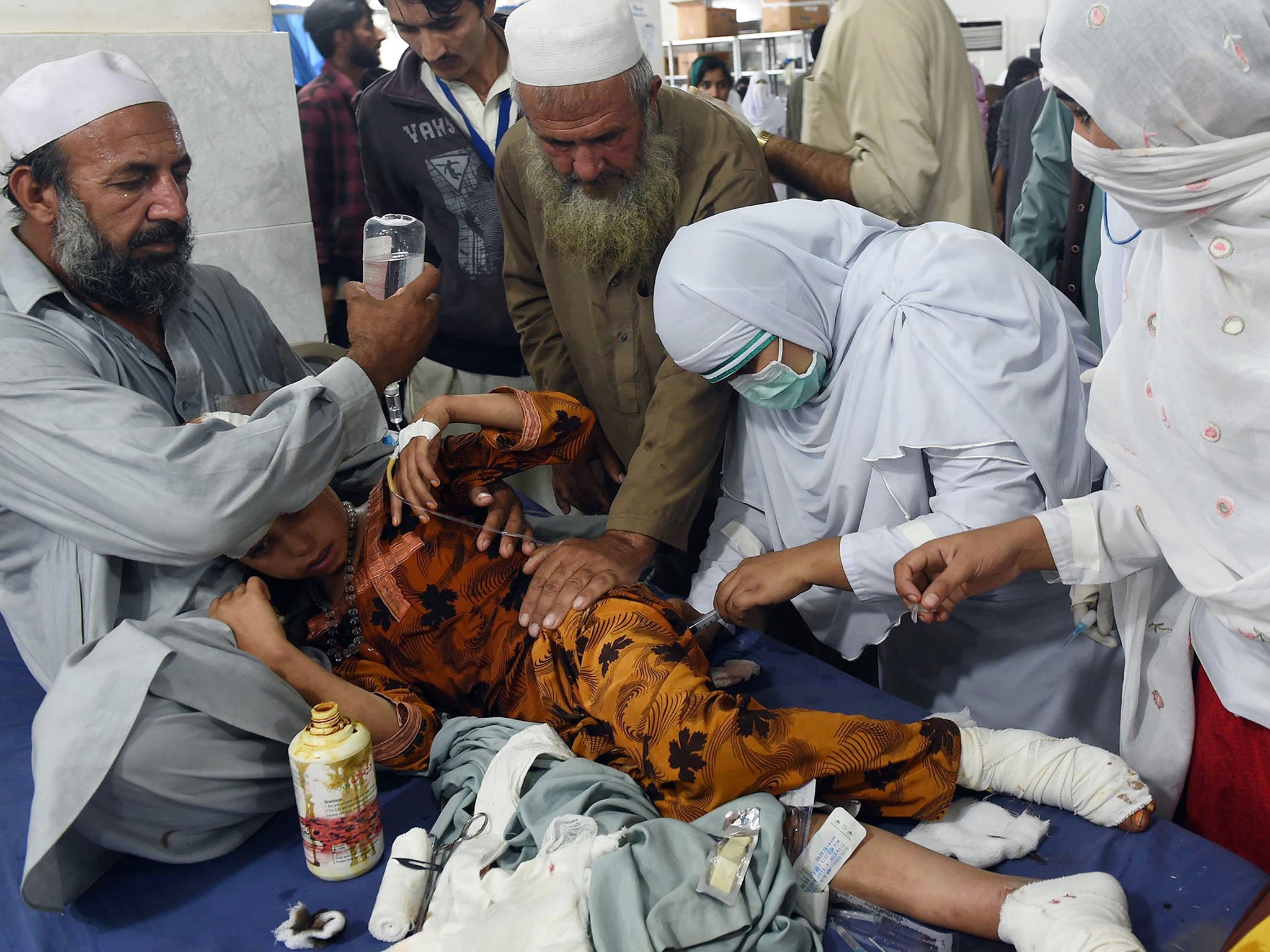 Pakistani paramedics treat a girl injured in an earthquake at a hospital in Peshawar