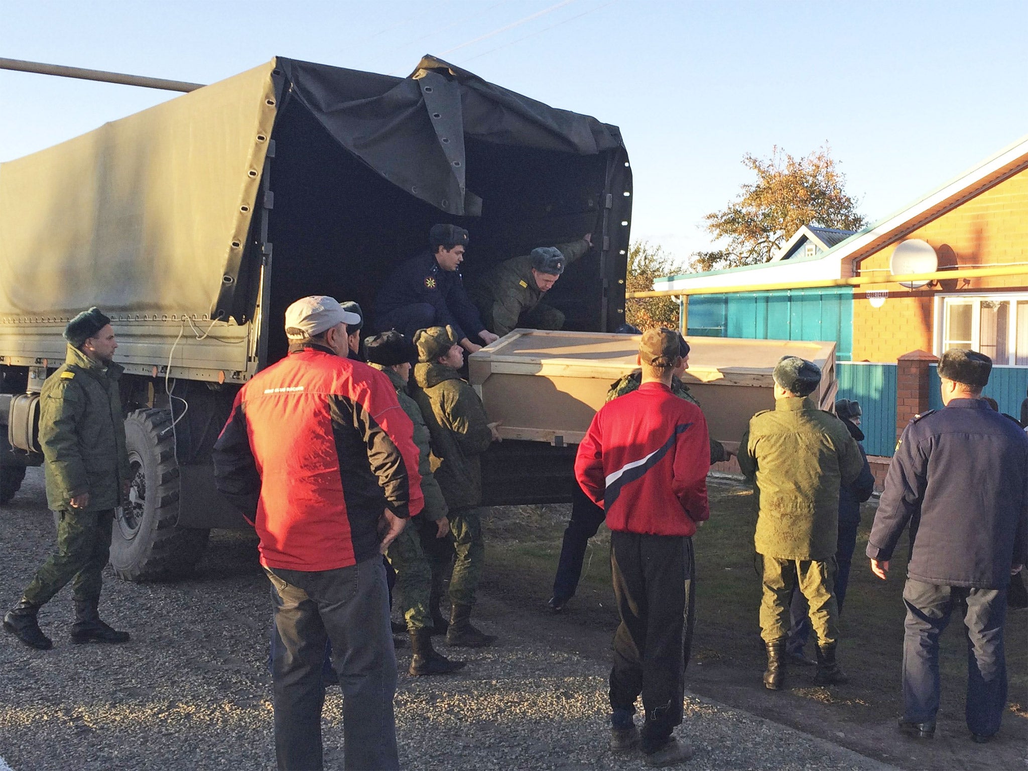 Russian servicemen unload a coffin containing the body of Vadim Kostenko from a truck near his family's home in the village of Grechnaya Balka, north-west of Krasnodar, Russia