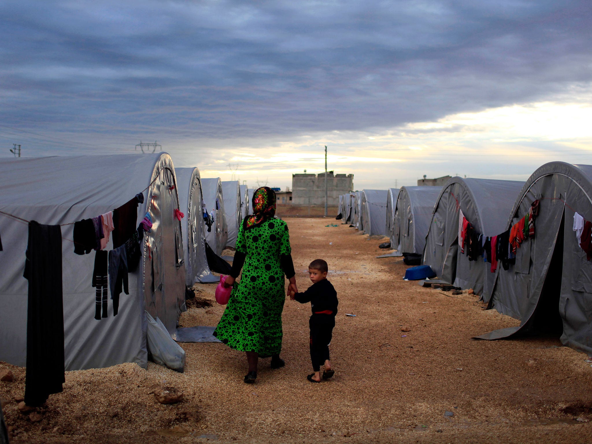 A Kurdish refugee mother and son from the Syrian town of Kobani walk beside their tent in a camp in the southeastern town of Suruc on the Turkish-Syrian border