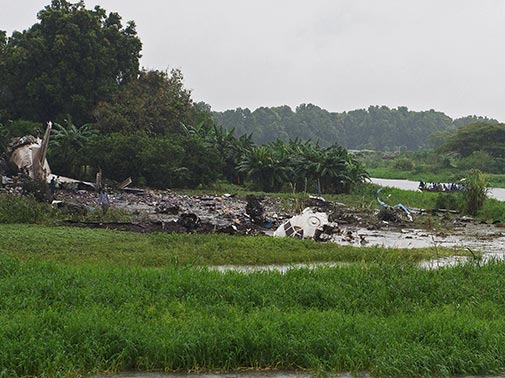 People gather at the site where the cargo plane crashed