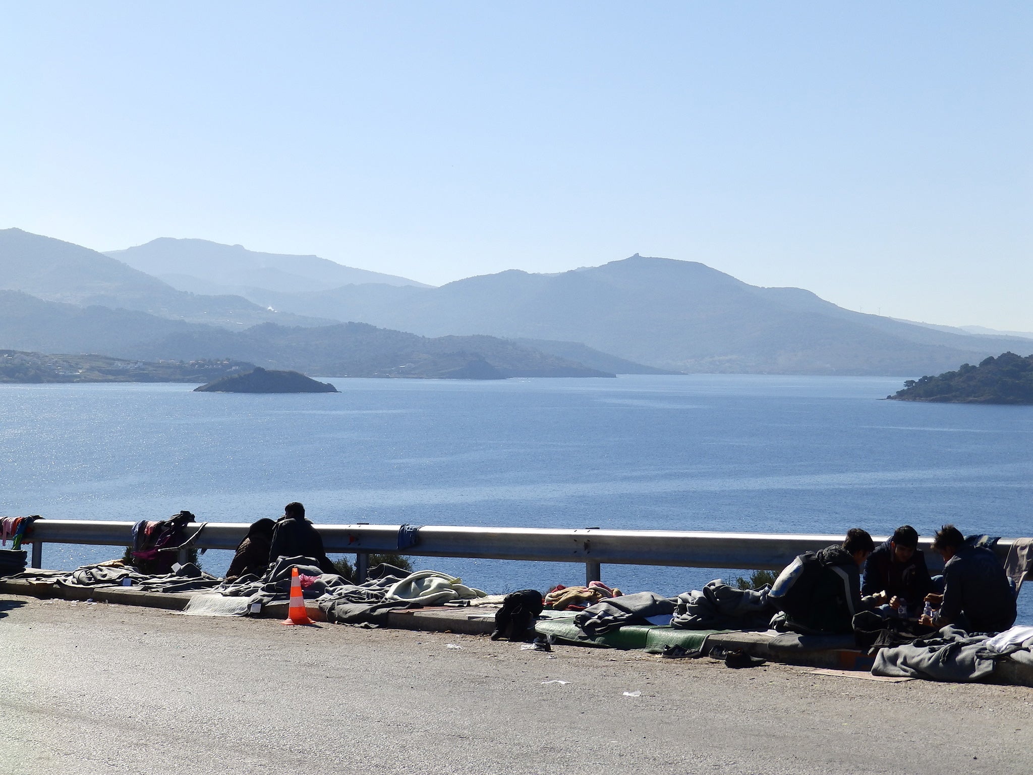 Refugees crowd a road looking over the Aegean near the Oxy transit camp on the island of Lesbos