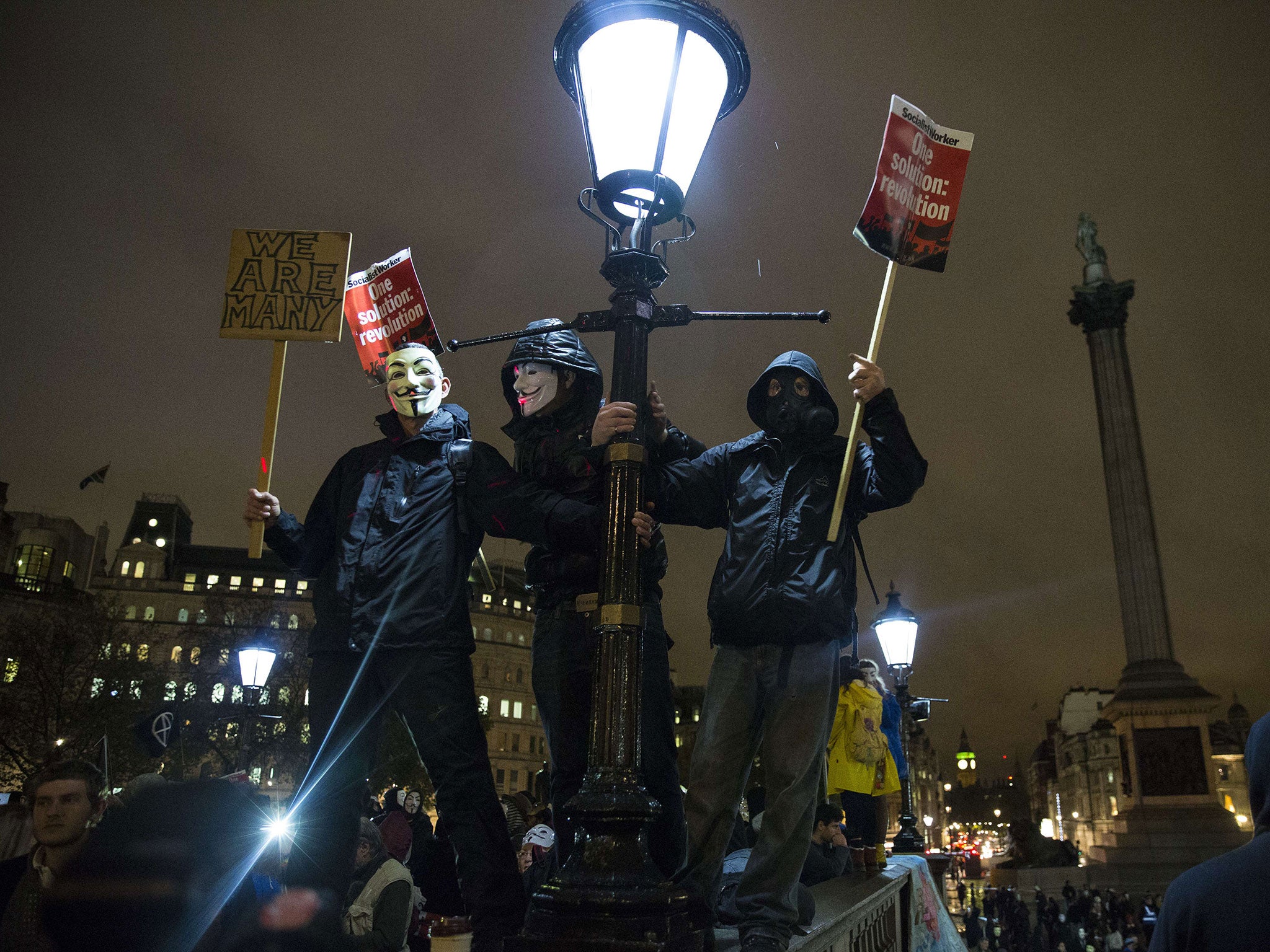 Masked figures wave their placards