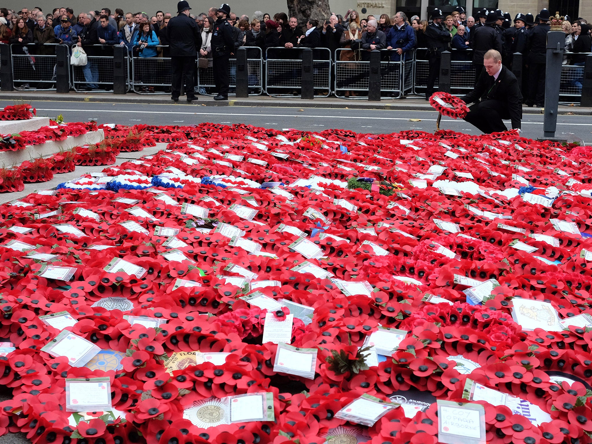 ​An attendant lays out poppy wreaths in London AP